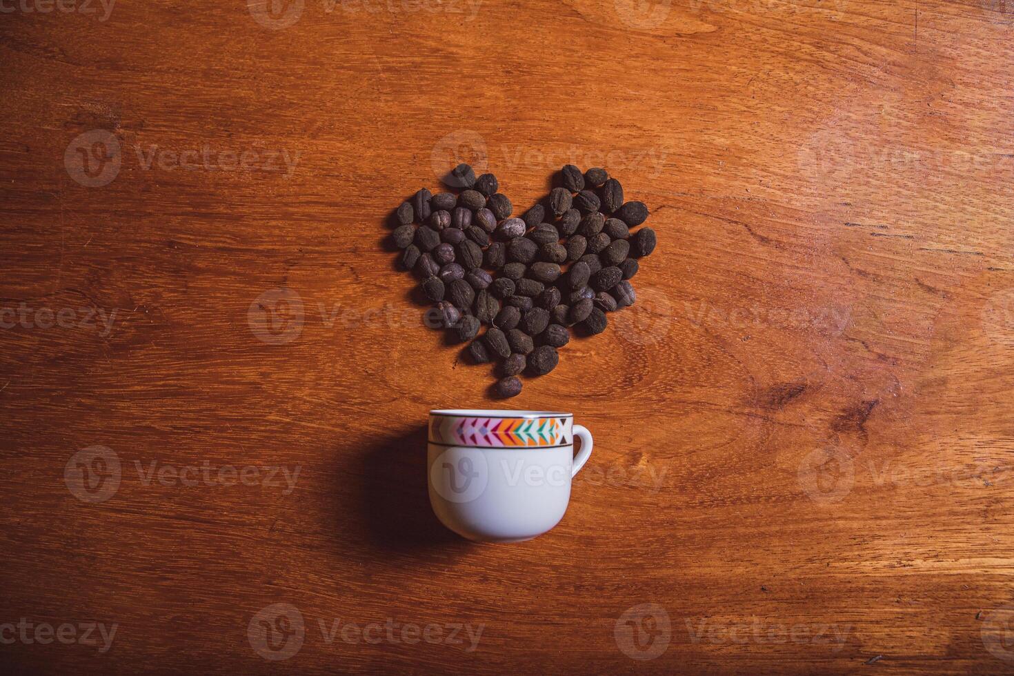 A cup of coffee with freshly harvested coffee beans in the shape of a heart photo