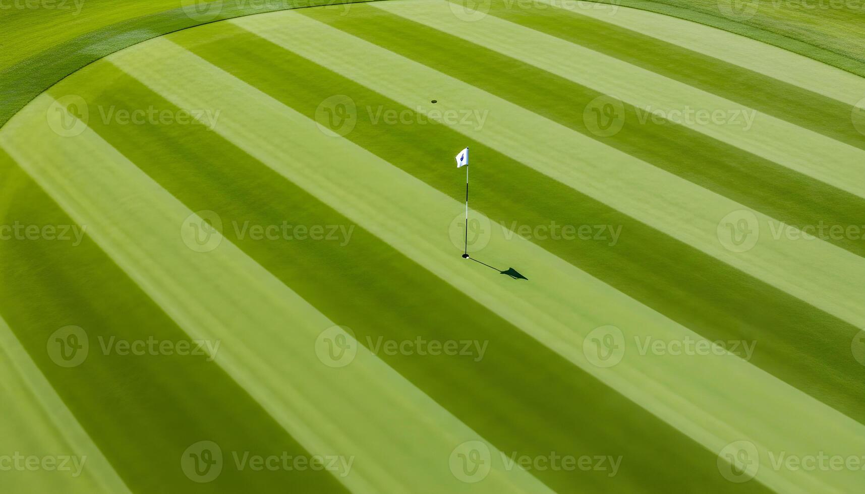 Aerial view of a pristine golf course with striped grass patterns and a small flag marking the hole photo