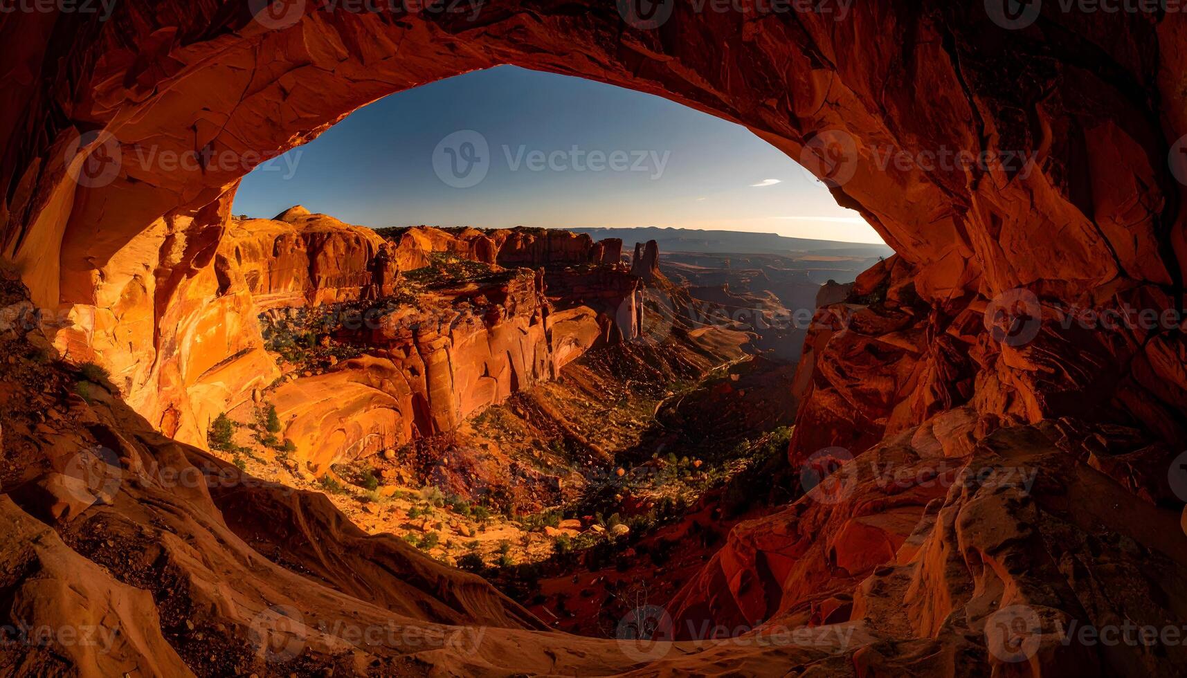 Scenic red rock canyon landscape seen from inside a natural arch at sunrise with distant mountain view photo