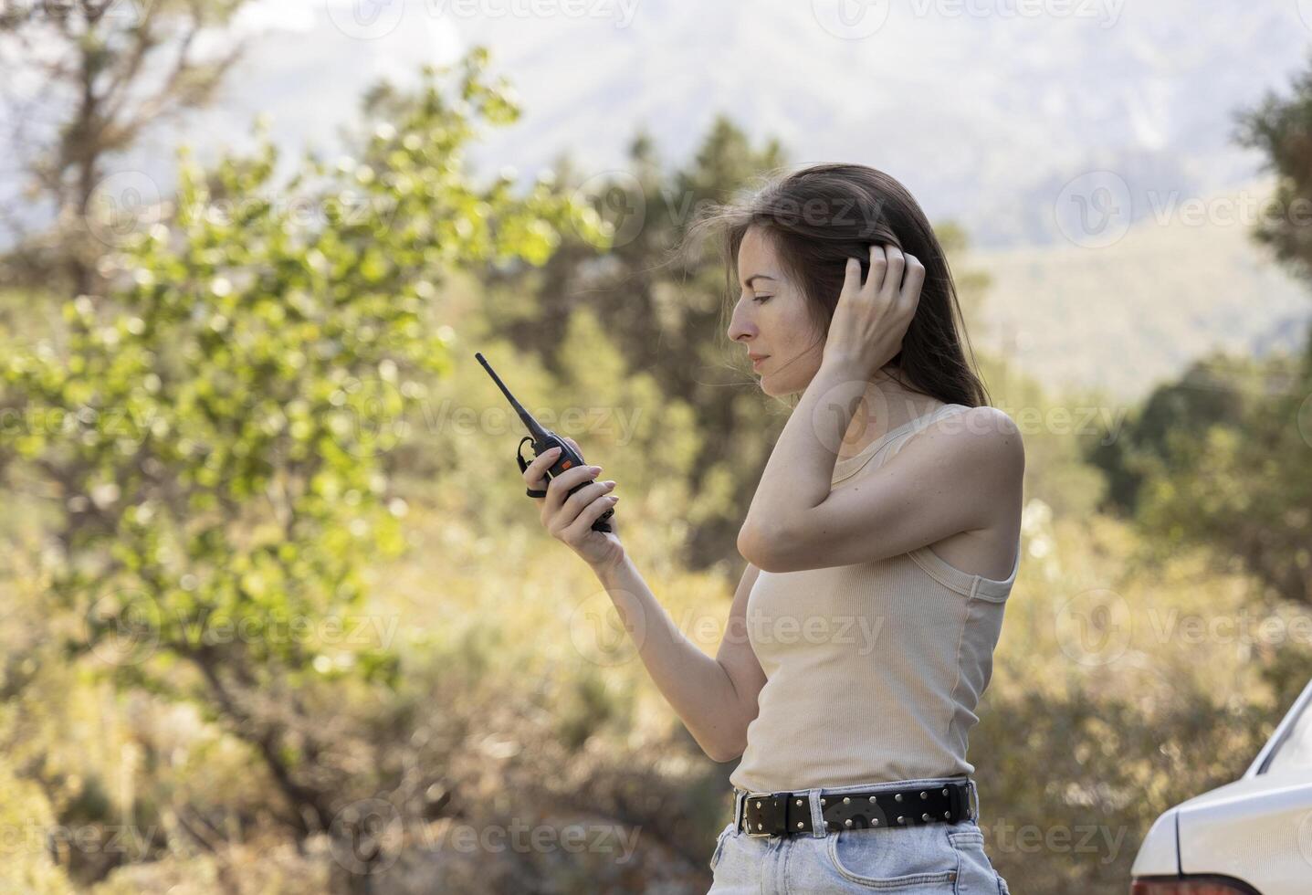 A woman with a walkie-talkie in the mountains symbolizes the spirit of adventure and readiness for extreme challenges. Suitable for promoting extreme sports, expeditions, and motivational content. photo