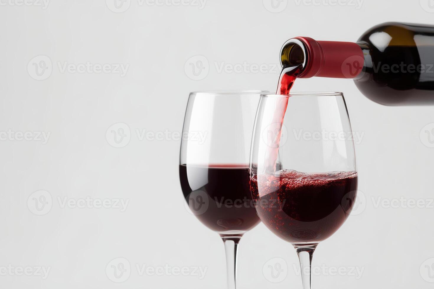 Red wine being poured into a wine glass on a gray background with area for text or design photo