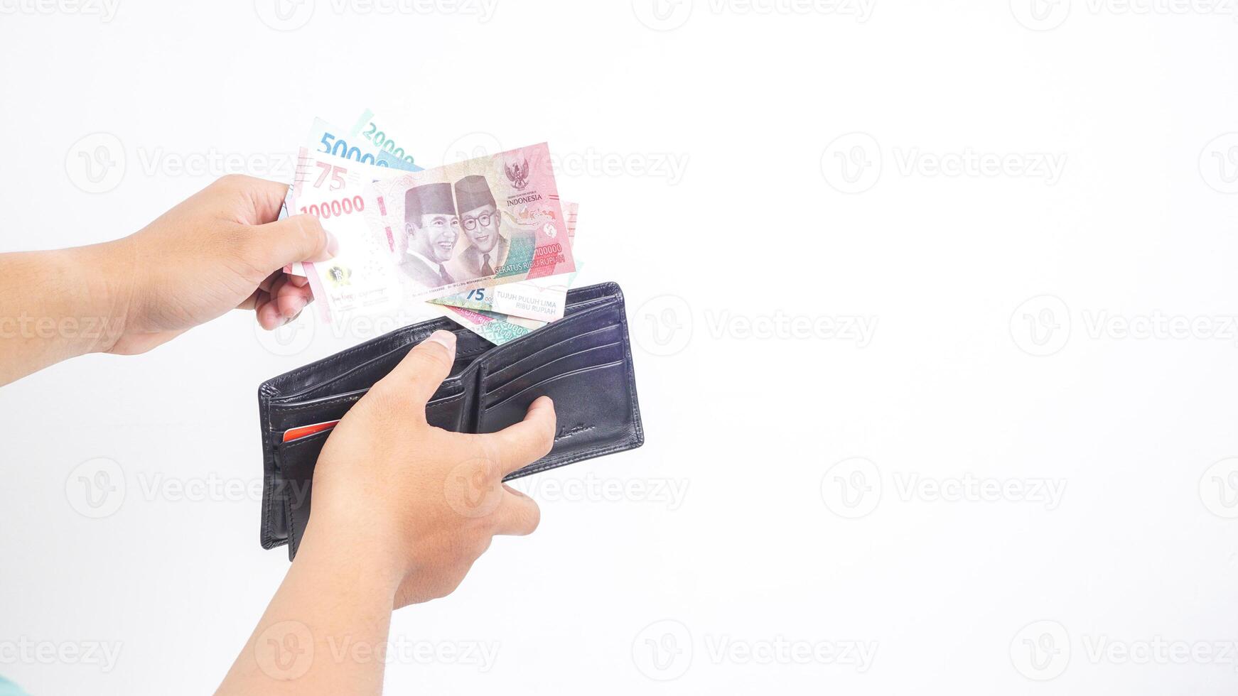 Yogyakarta, Indonesia, 2025 - Hand taking several Indonesian Rupiah banknotes with different values from wallet isolated on white background photo