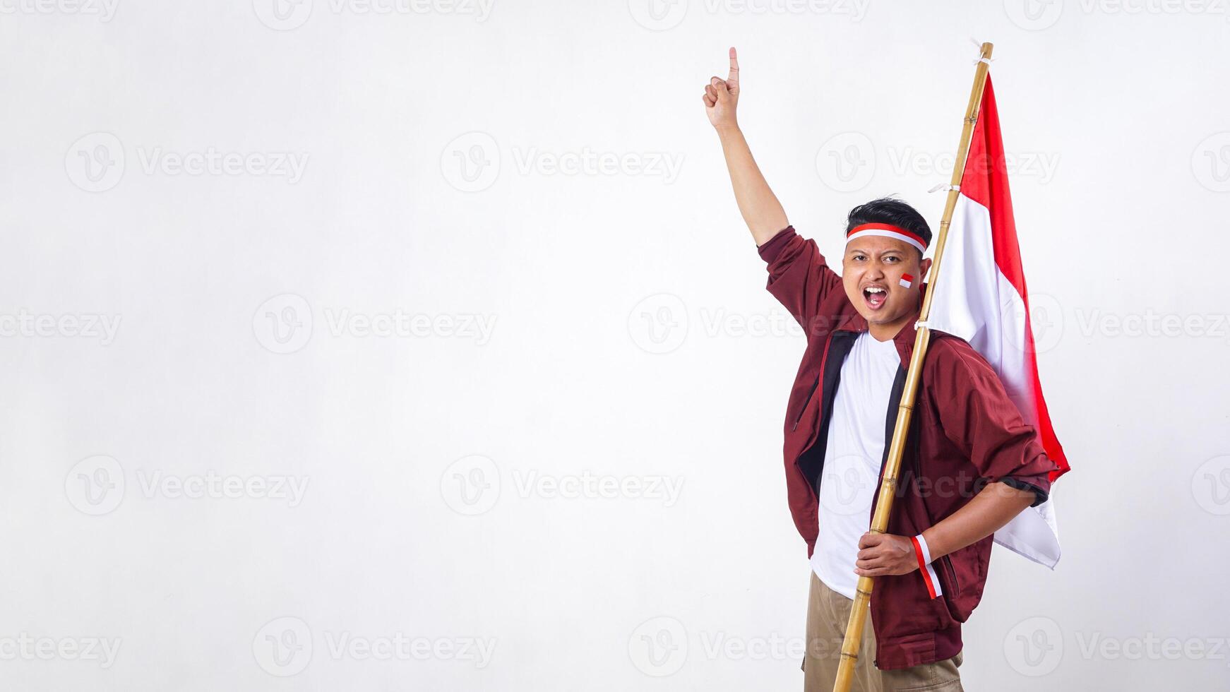 Indonesian man holding stick with red and white flag of Indonesia and showing number one sign with finger isolated on white background photo
