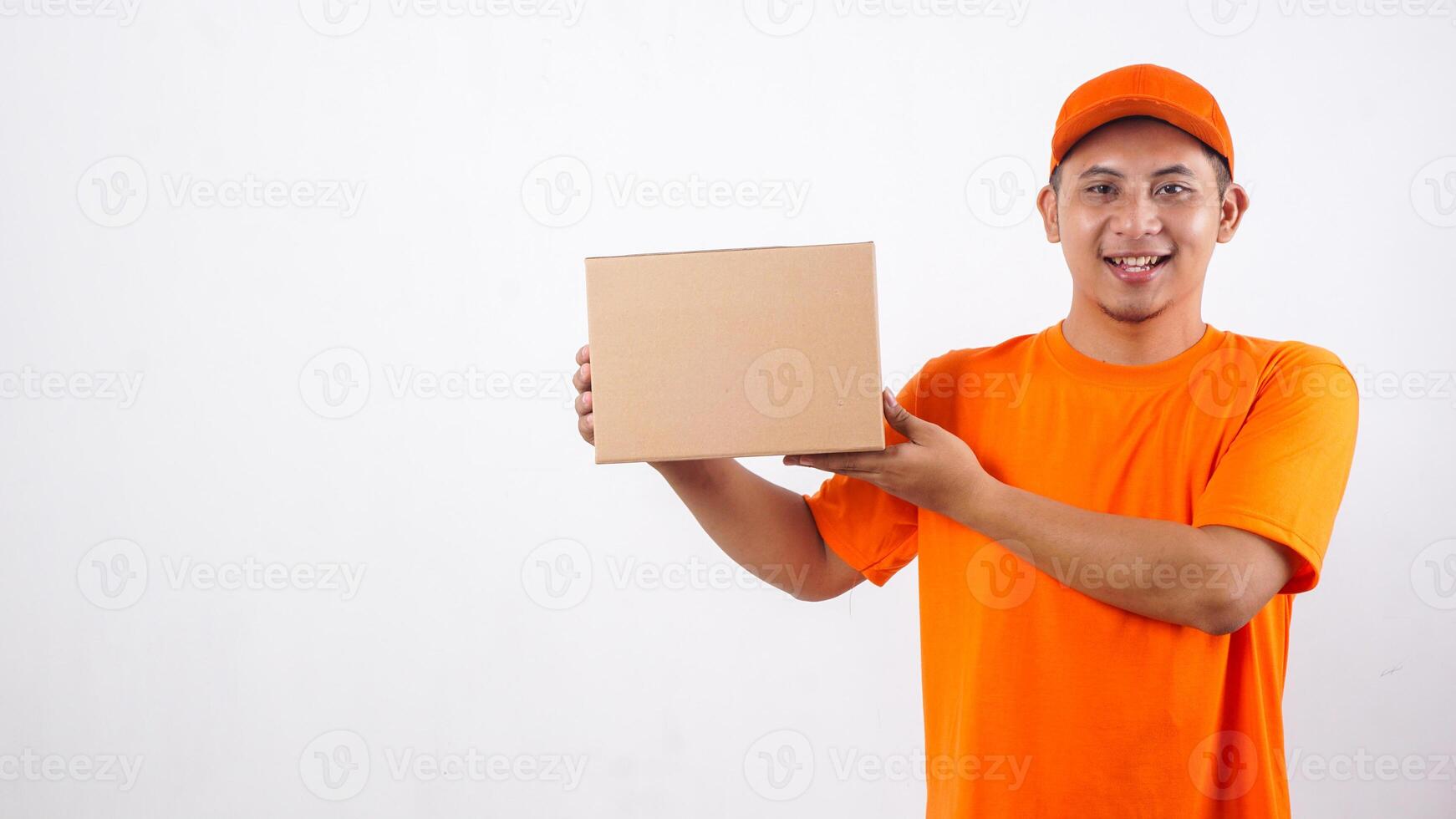 Smiling Asian deliveryman in orange t-shirt uniform with a package box parcel isolated on white background photo