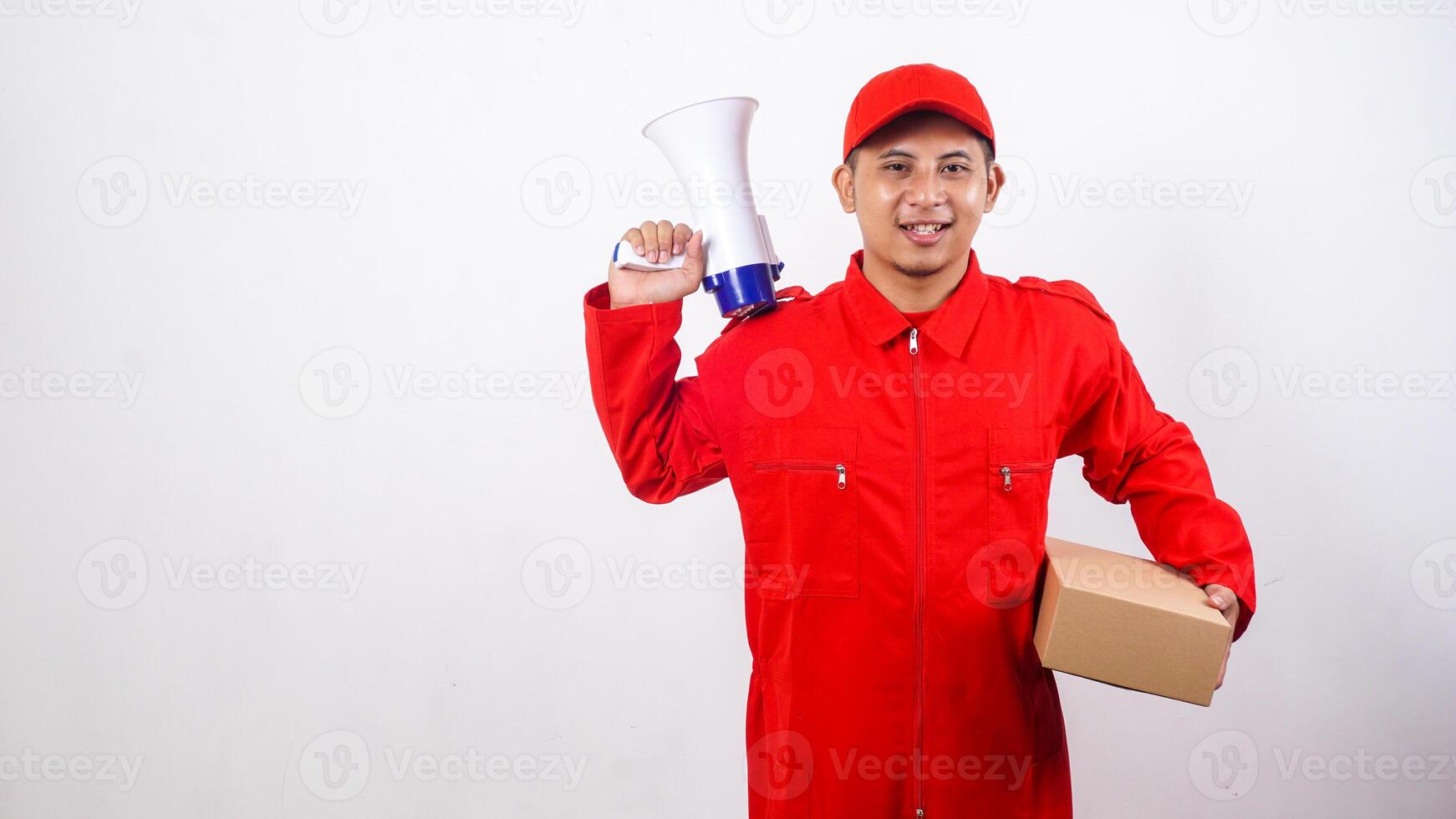 Asian Delivery man in red uniform carrying a package box parcel while holding megaphone on his shoulder isolated on white background photo