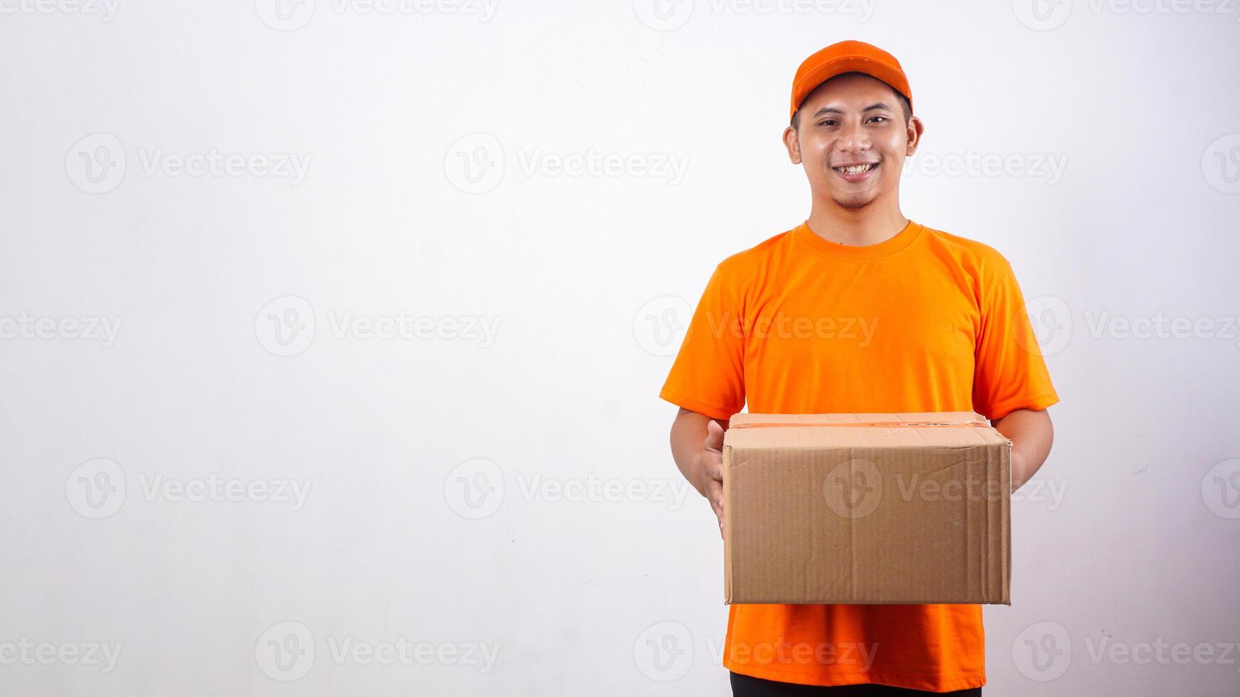 Portrait of smiling Asian deliveryman in orange t-shirt uniform holding a package box parcel isolated on white background photo