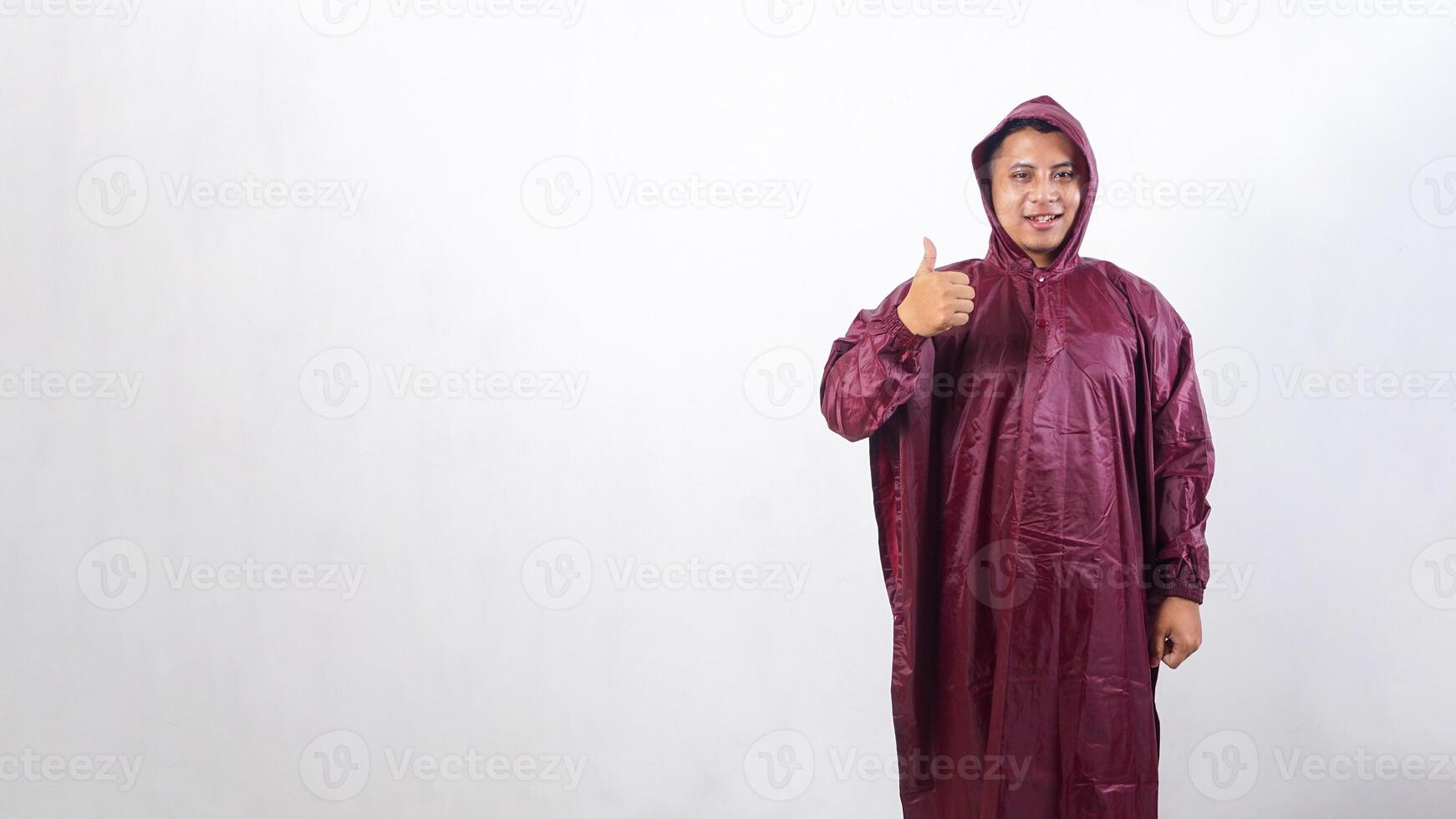 Smiling Asian man in red raincoat showing his thumb up isolated on white background photo