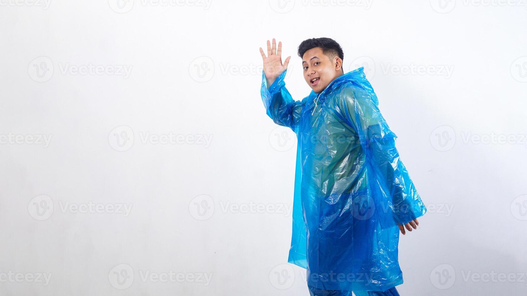 Asian young man in rain poncho showing gesture of greeting isolated on white background photo