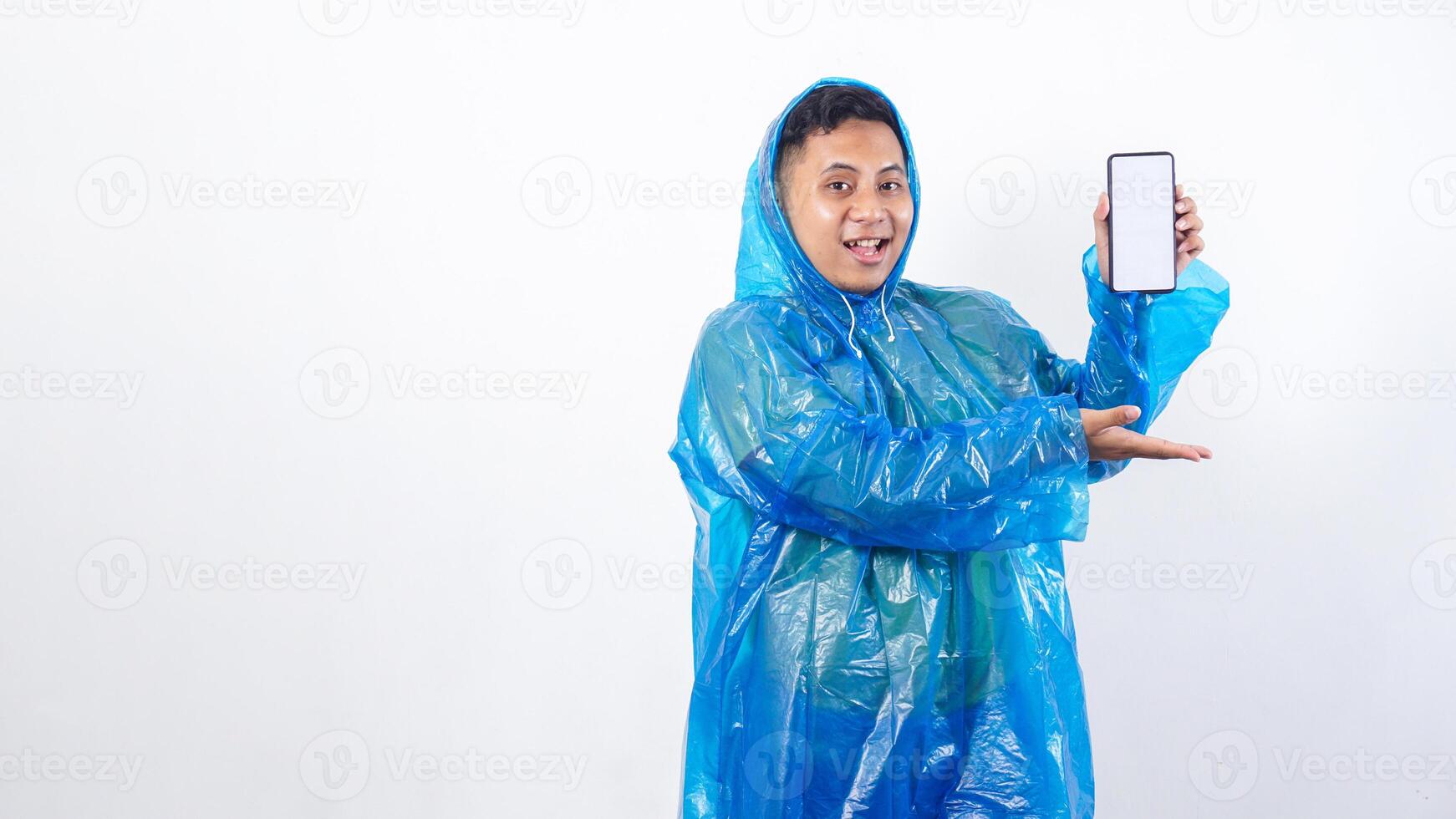Portrait of Asian young man in blue raincoat presenting smartphone mock up with blank screen isolated on white background photo