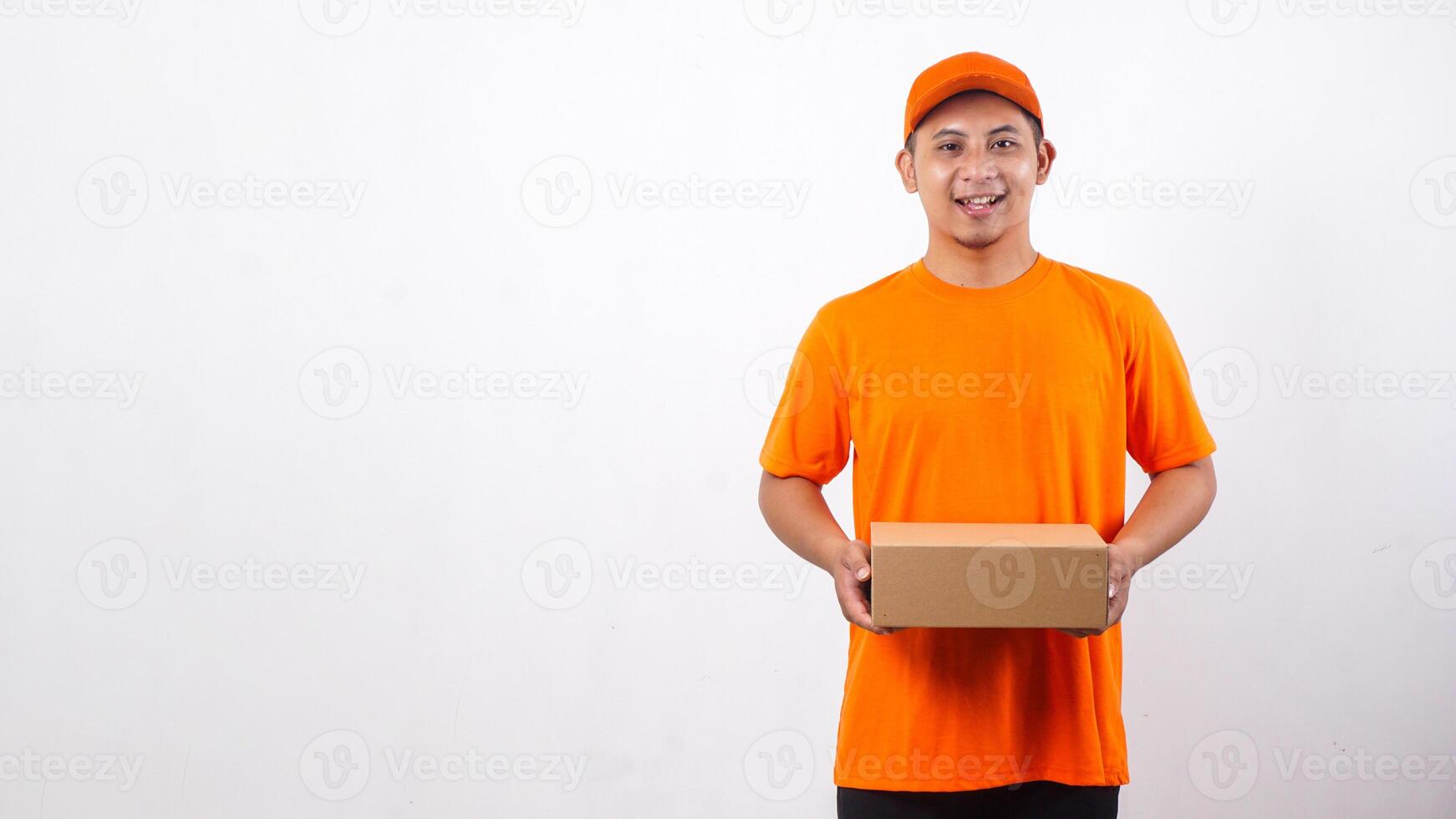 Asian deliveryman in orange t-shirt uniform carrying a package box parcel isolated on white background photo