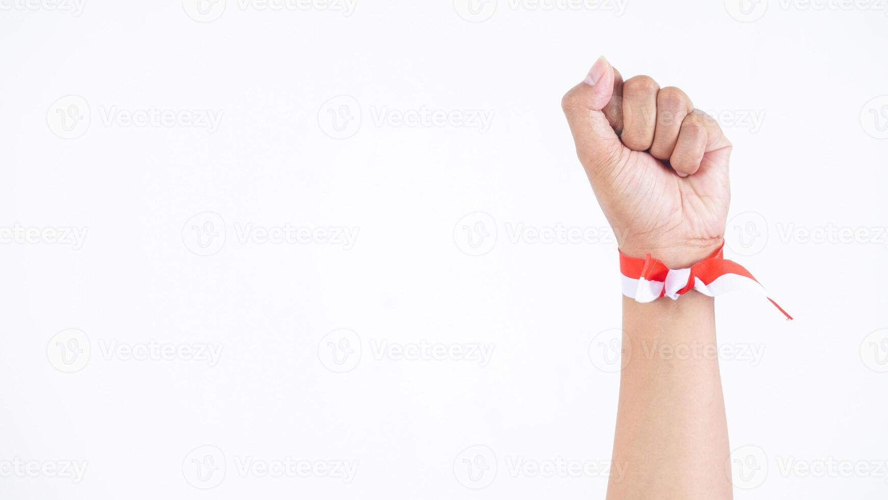 Hand tie the wrist with red and white ribbon and clenched in the air to celebrate Indonesia independence day isolated on white background photo