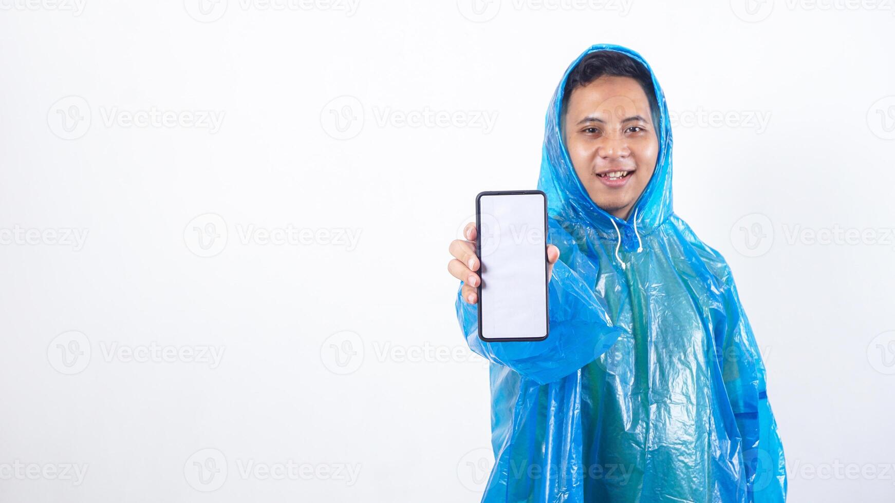 Asian young man in blue raincoat showing smartphone mock up with blank screen isolated on white background photo
