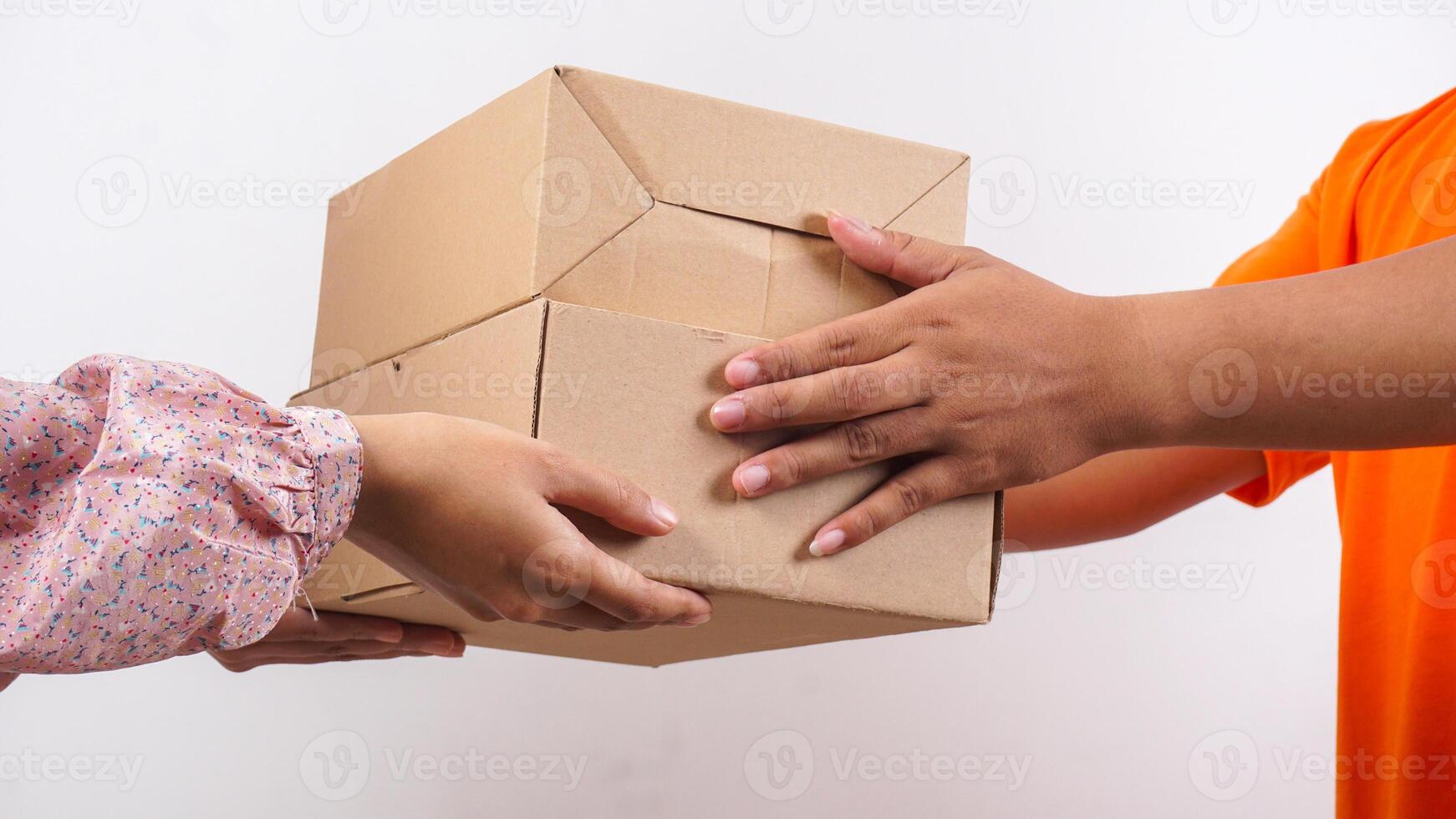 Close up of customer taking a package box given by delivery man in orange t-shirt isolated on white background photo