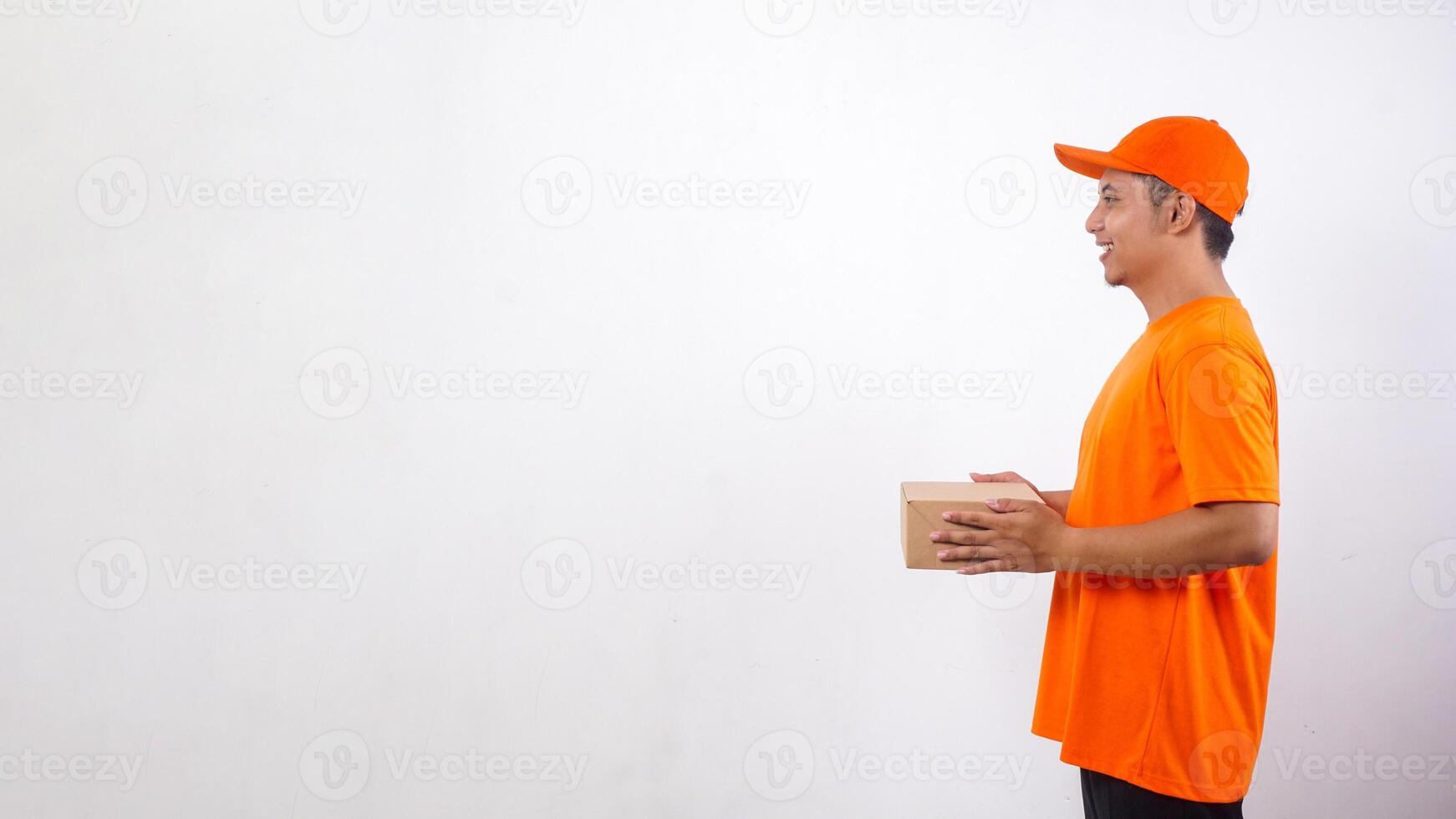 Side view of Asian deliveryman in orange t-shirt uniform holding a package box parcel isolated on white background photo