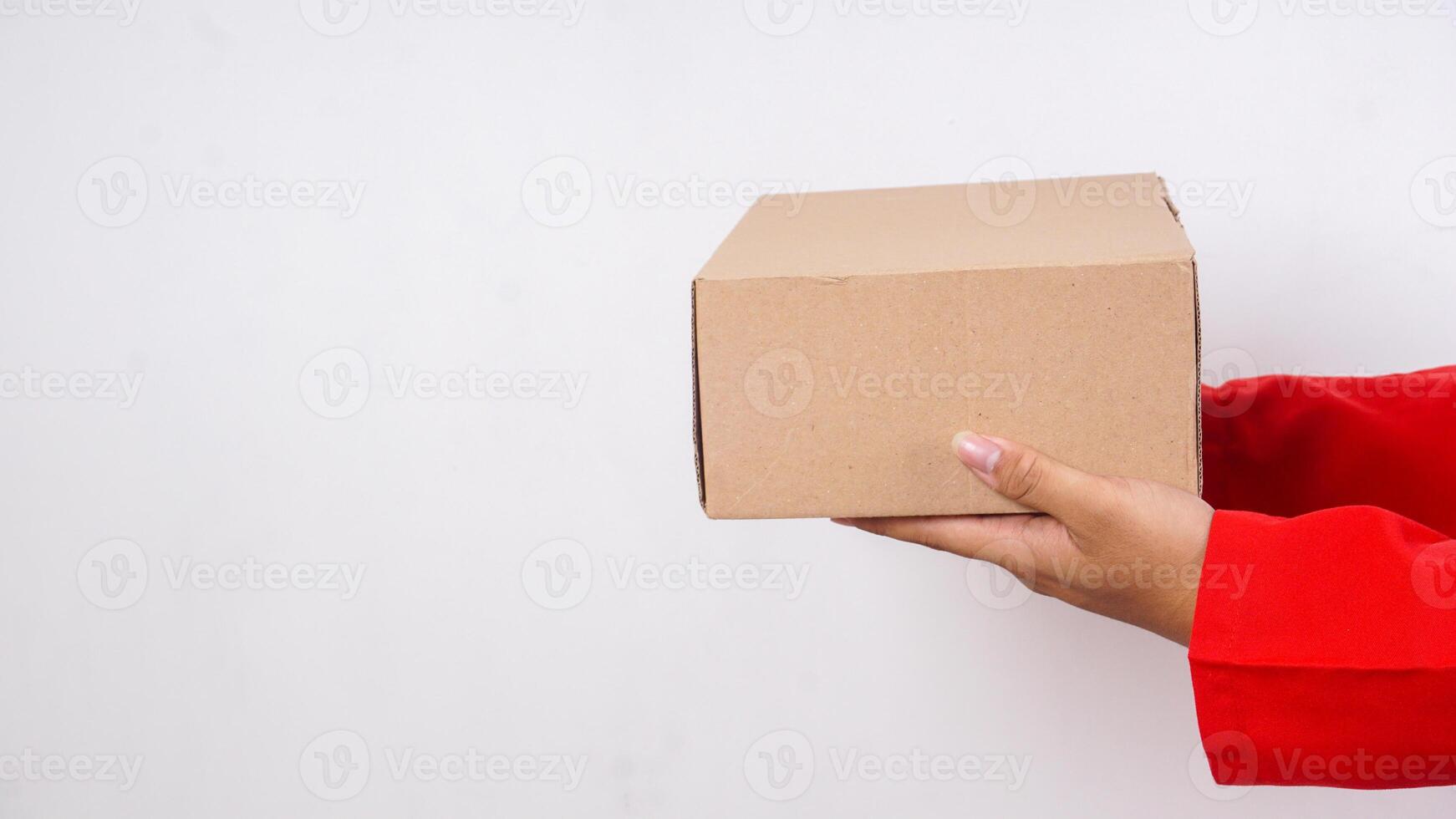 Close up of delivery man in red uniform with a package box parcel to deliver to customer isolated on white background photo