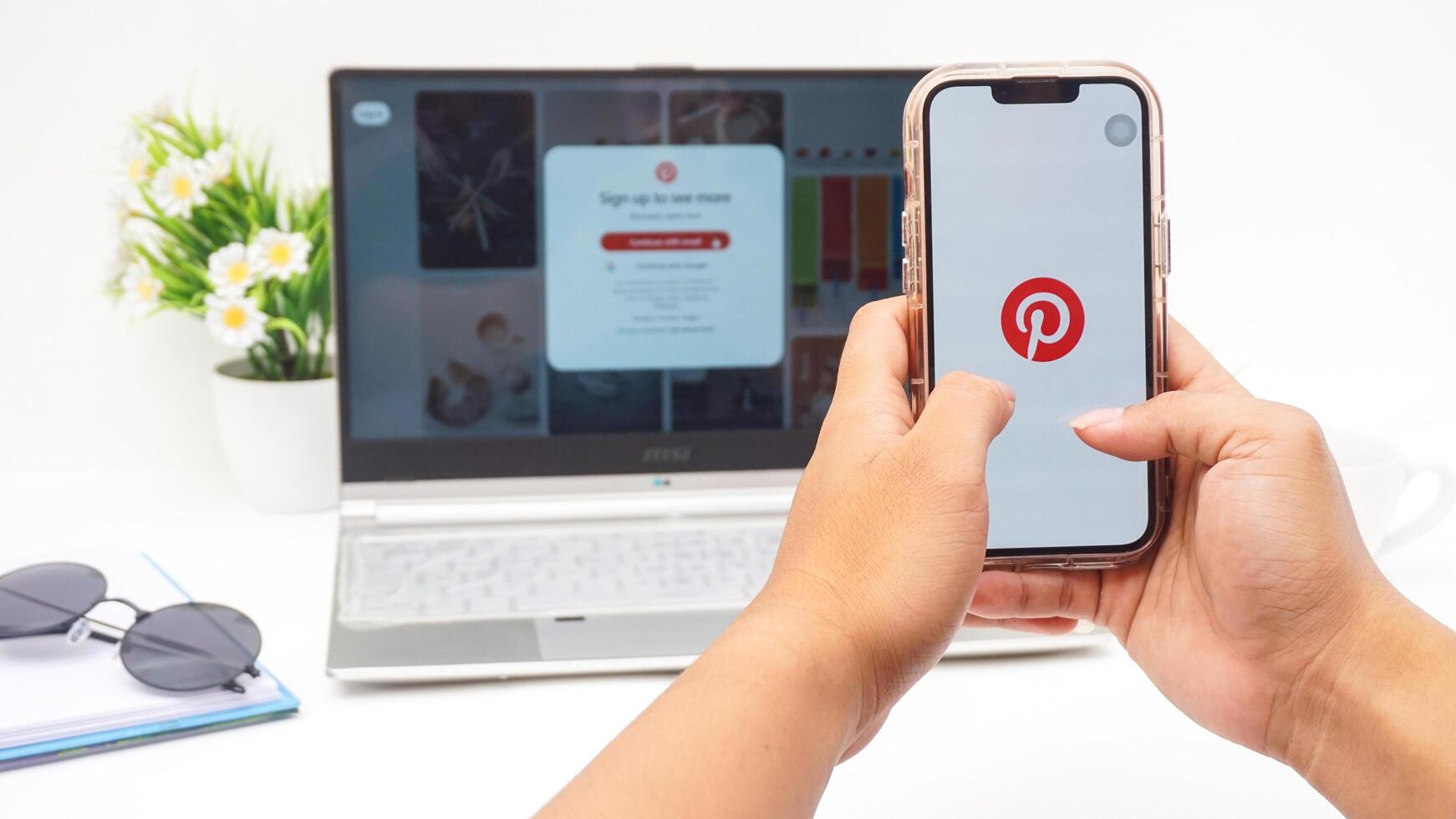 Yogyakarta, Indonesia, April 2025 - Hand with smartphone that shows front page of Pinterest, visual discovery platform application on the screen isolated on white background photo