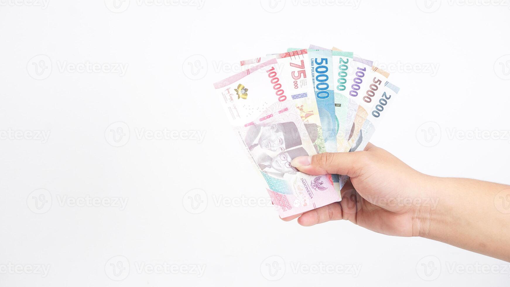Yogyakarta, Indonesia, 2025 - Hand holding several Indonesian Rupiah banknotes with different values isolated on white background photo