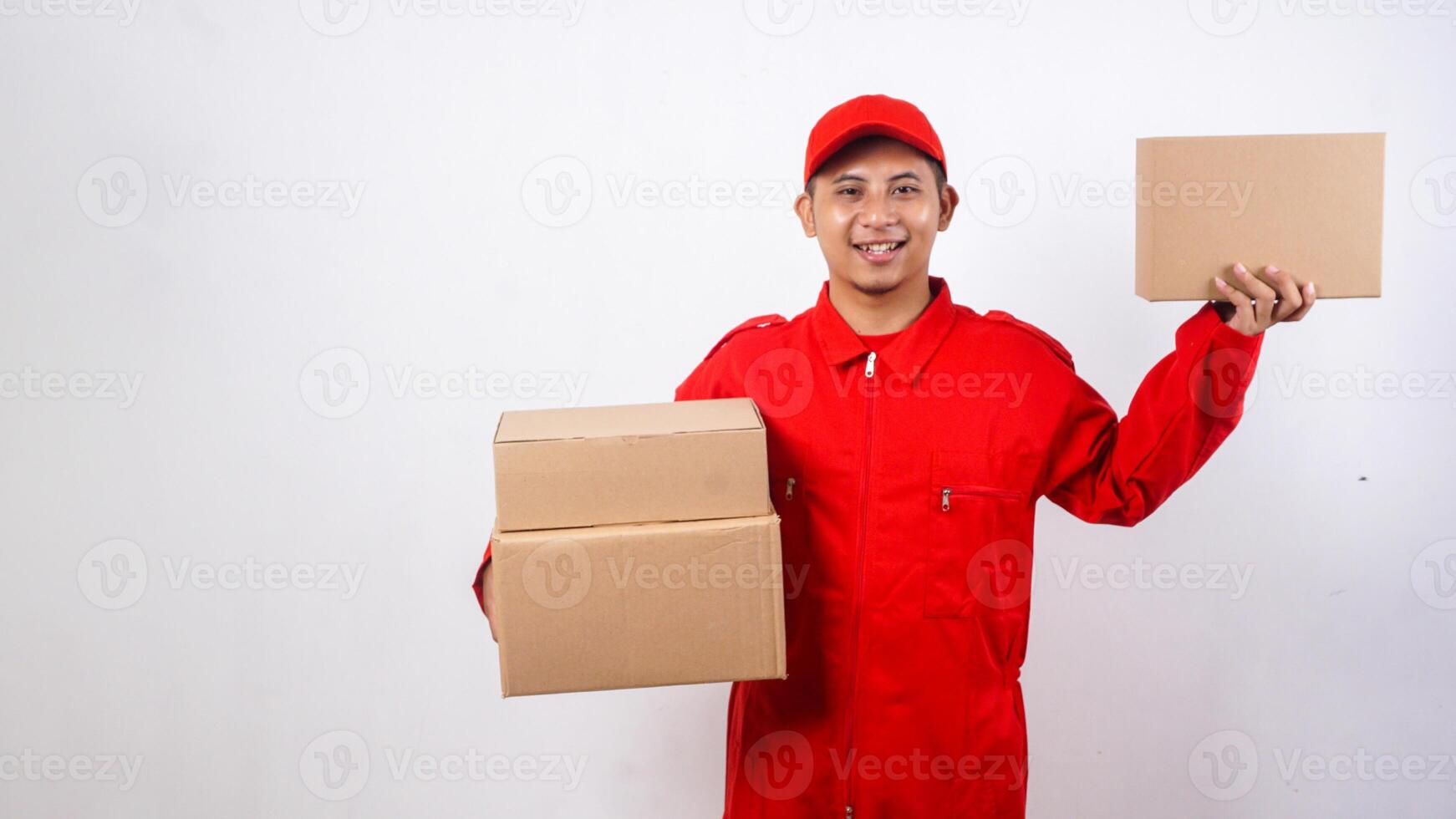 Delivery man in red uniform carrying package boxes and showing other package box to customer to camera isolated on white background photo