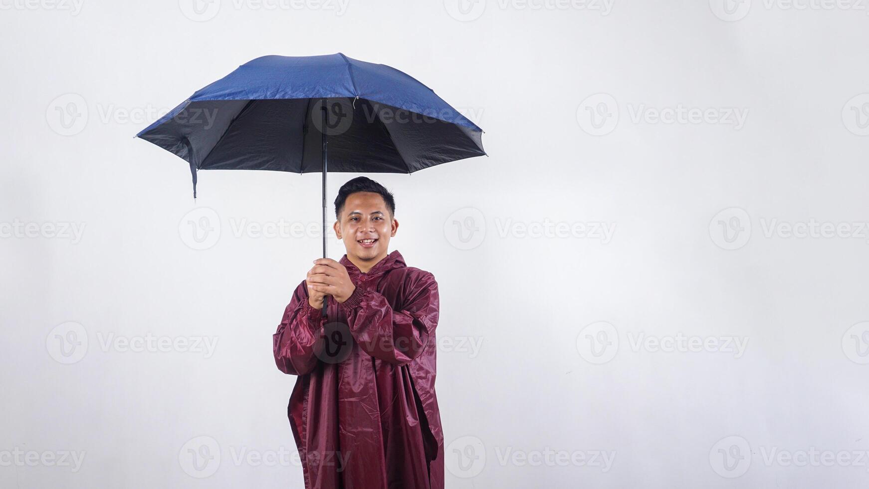 Smiling Asian man in red raincoat holds umbrella isolated on white background photo