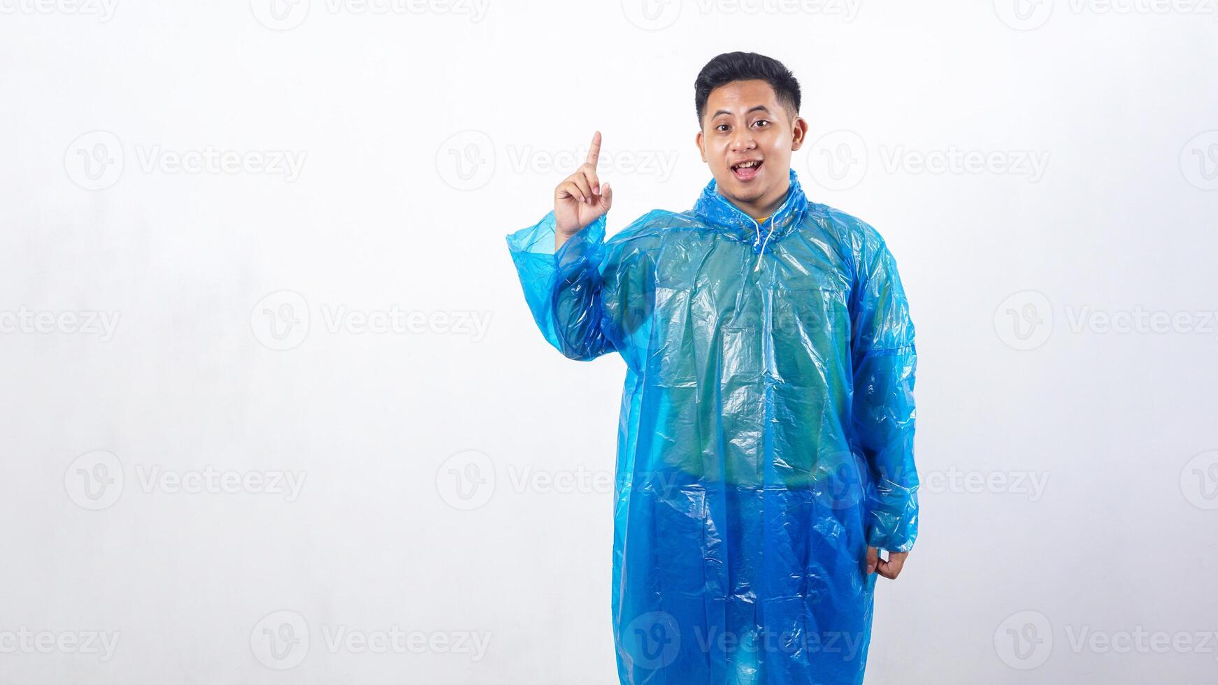 Asian young man in rain poncho showing number one gesture isolated on white background photo