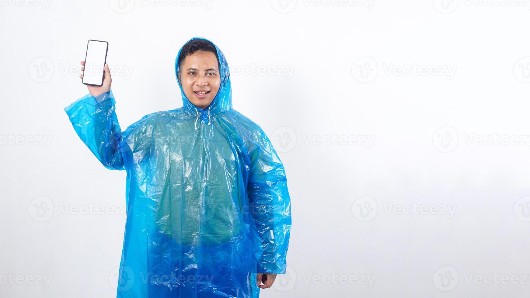Portrait of Asian young man in blue raincoat showing smartphone mock up with blank screen isolated on white background photo