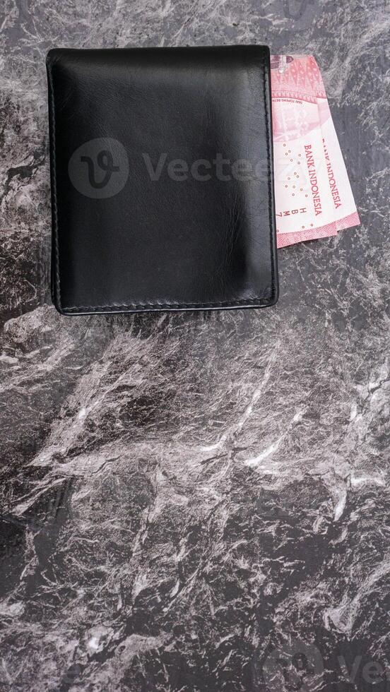 Yogyakarta, Indonesia, 2025 - Wallet with several Indonesian Rupiah banknotes in it isolated on pattern background photo