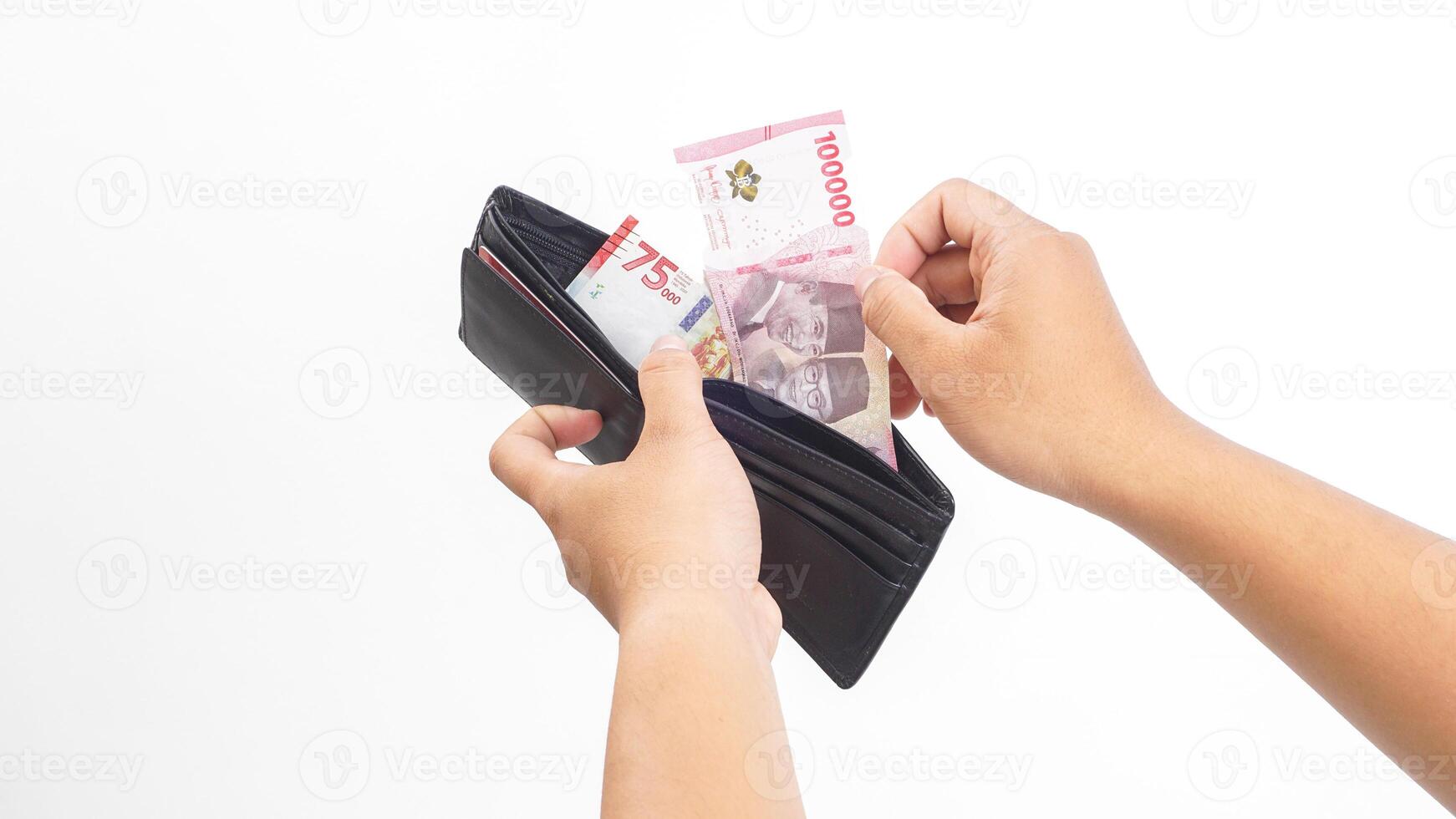 Yogyakarta, Indonesia, 2025 - Hand open a wallet and taking several Indonesian Rupiah banknotes with different values from it isolated on white background photo