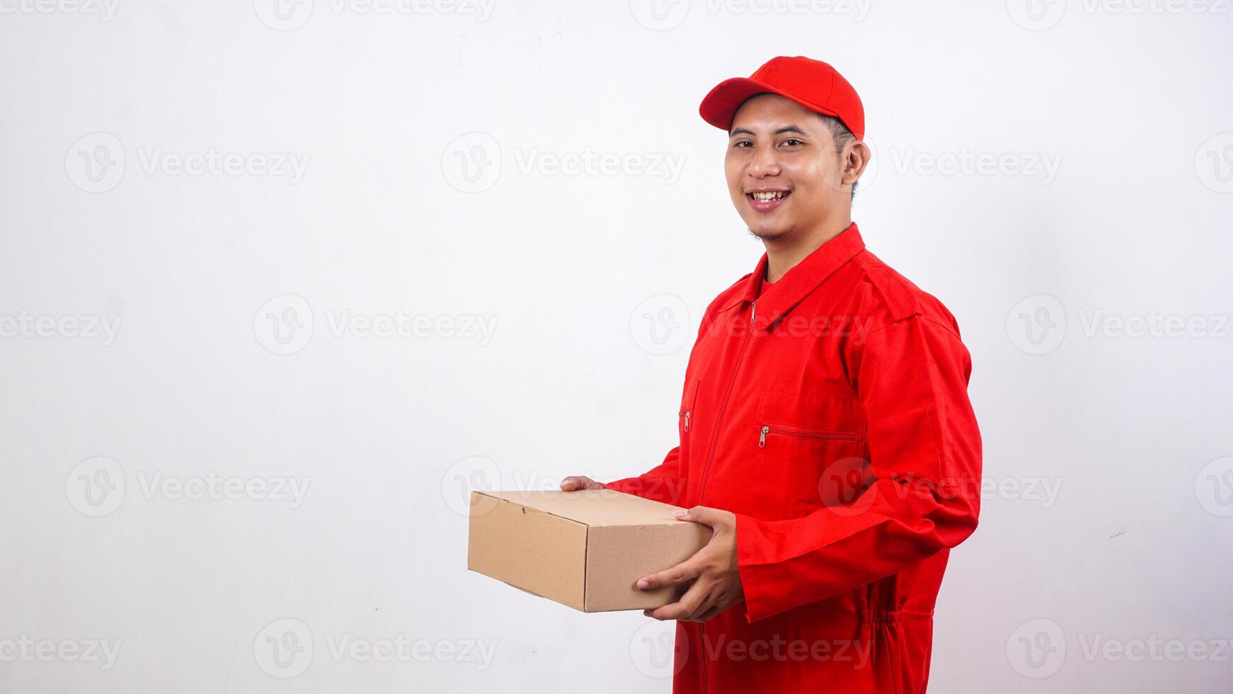 Smiling Asian Delivery man in red uniform holding package box parcel isolated on white background photo