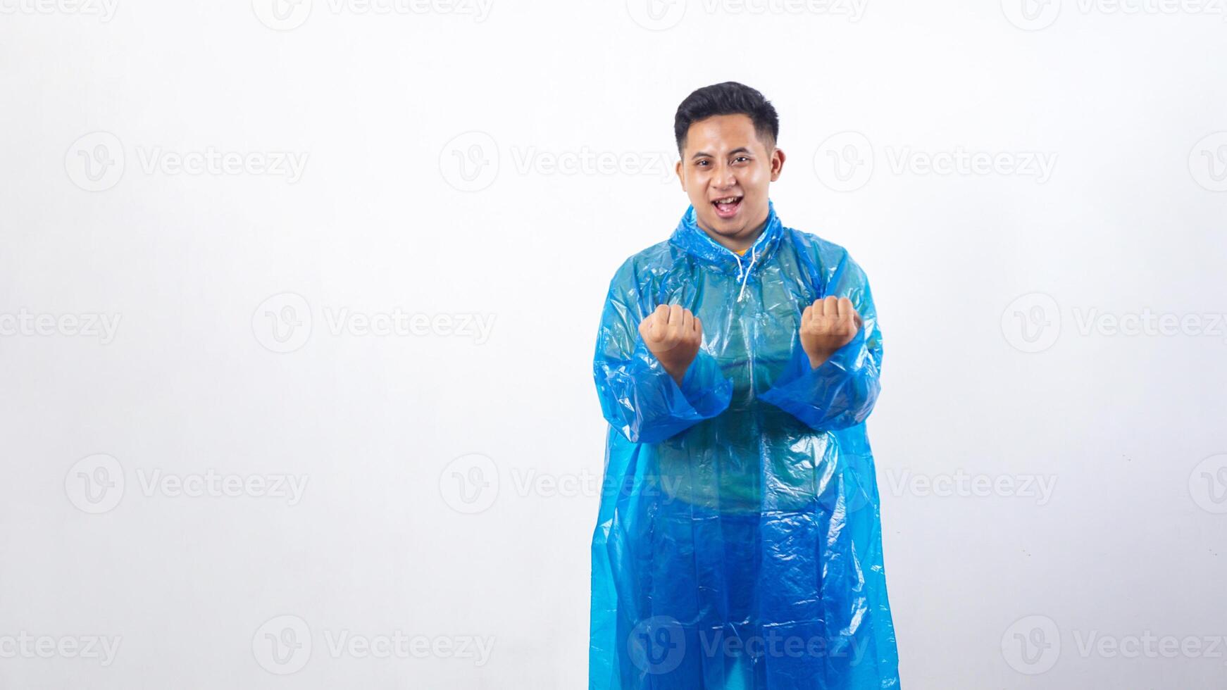 Happy Asian young man in rain poncho showing his fists isolated on white background photo