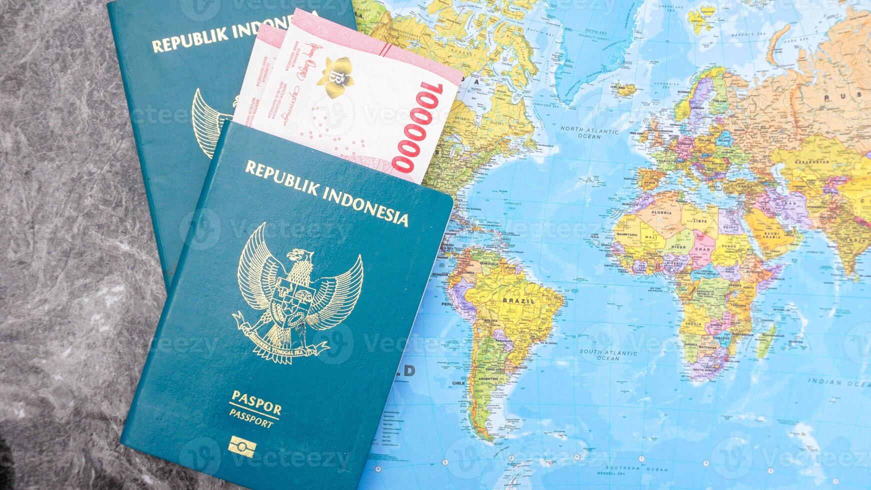 Yogyakarta, Indonesia, 2025 - Indonesian passports with Indonesia Rupiah banknotes and world map isolated on marble pattern background photo