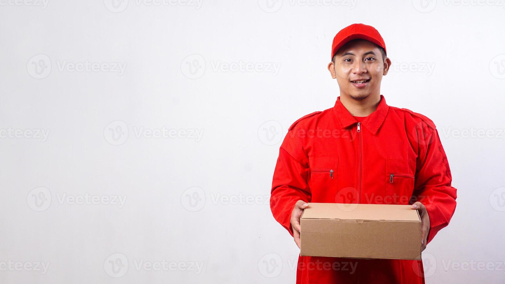 Delivery man in red uniform holding cardboard parcel box isolated on white background photo