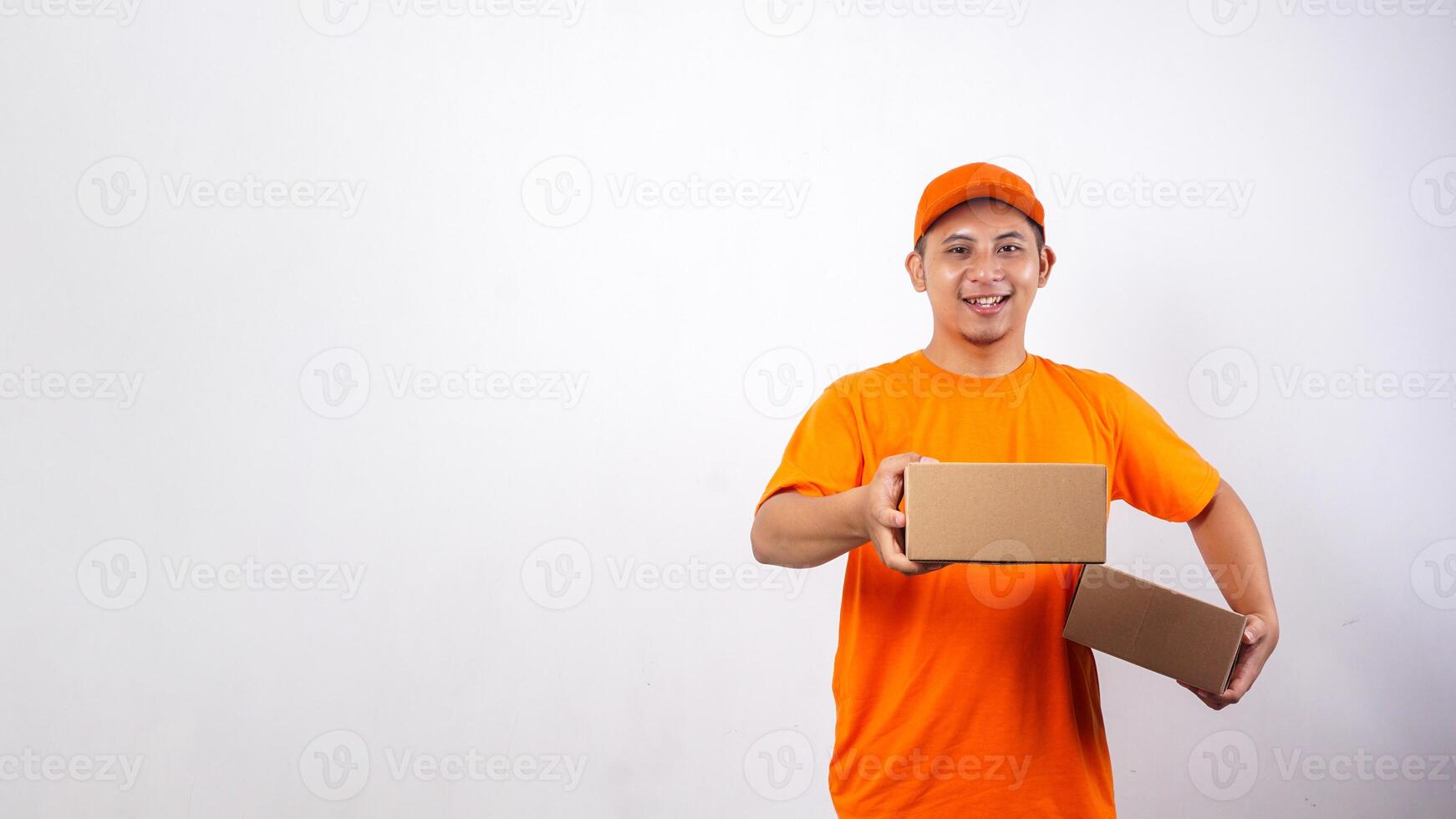 Asian deliveryman in orange t-shirt uniform carrying package box parcel and giving other package box to customer isolated on white background photo