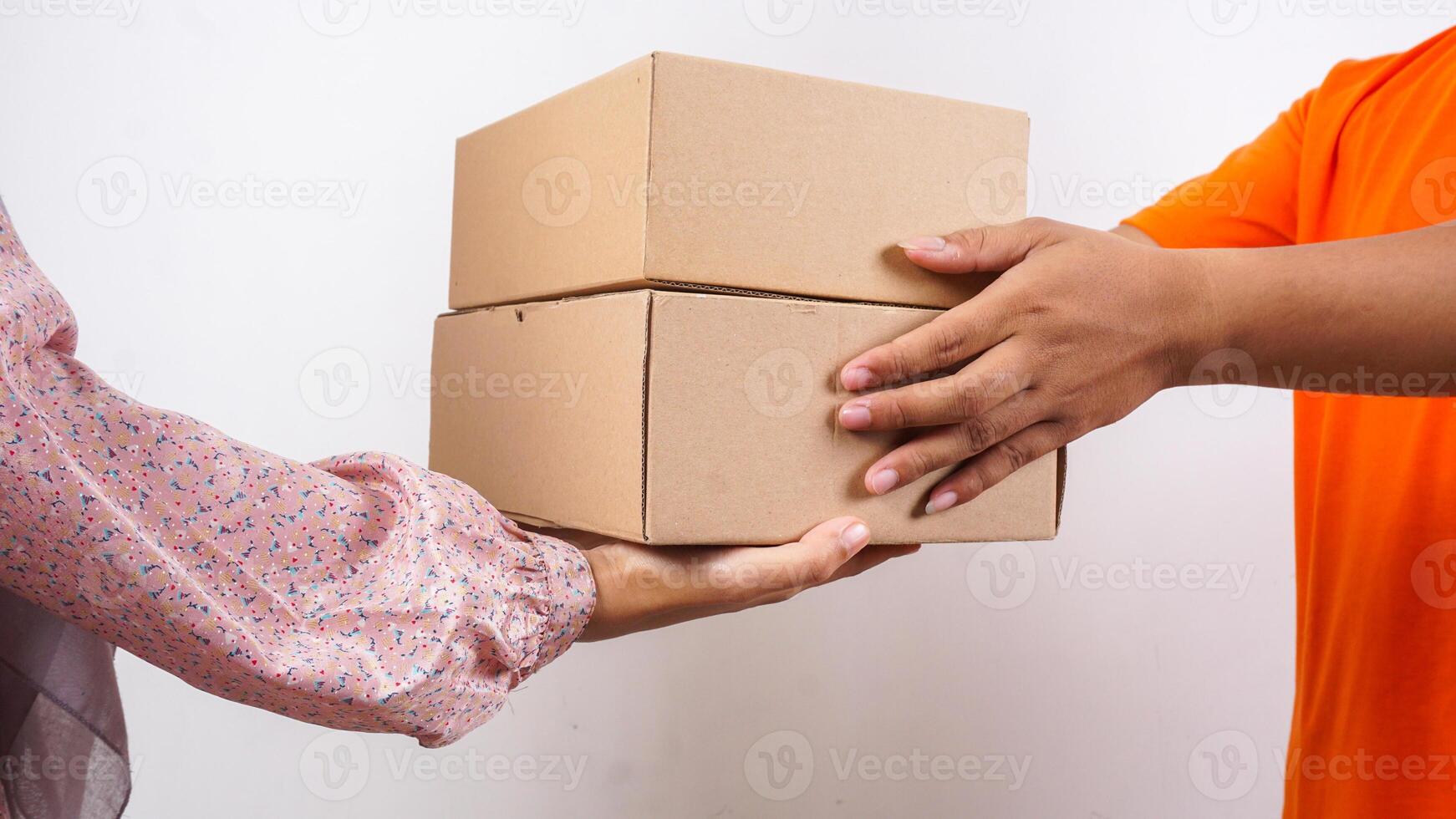 Close up of customer taking package boxes parcel delivered by delivery man in orange t-shirt isolated on white background photo