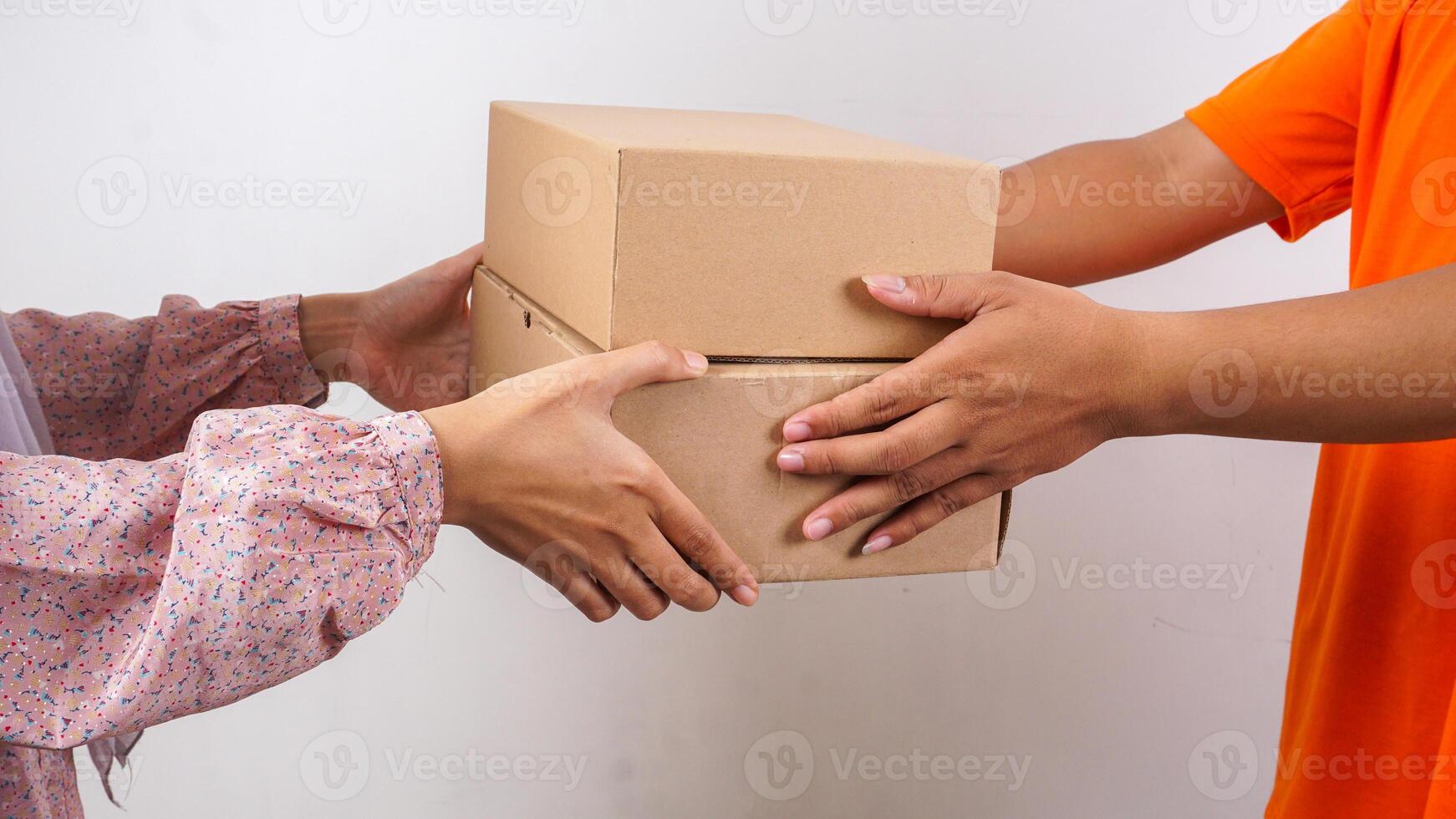 Close up of customer taking package boxes parcel given by delivery man in orange t-shirt isolated on white background photo