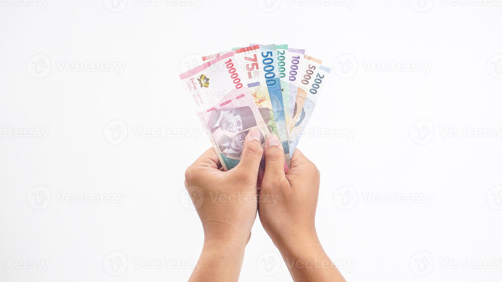 Yogyakarta, Indonesia, 2025 - Hands holding several Indonesian Rupiah banknotes with different values isolated on white background photo