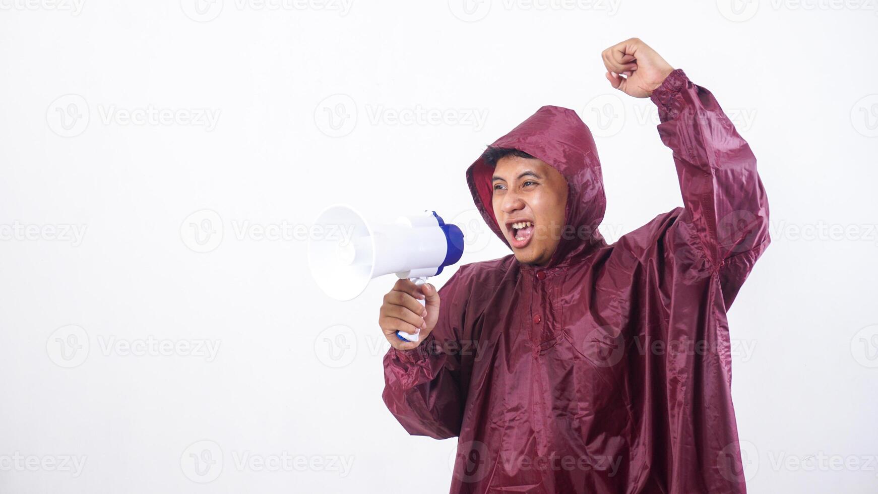 Asian man in red raincoat shout using megaphone and raising his clenched fist into the air isolated on white background photo