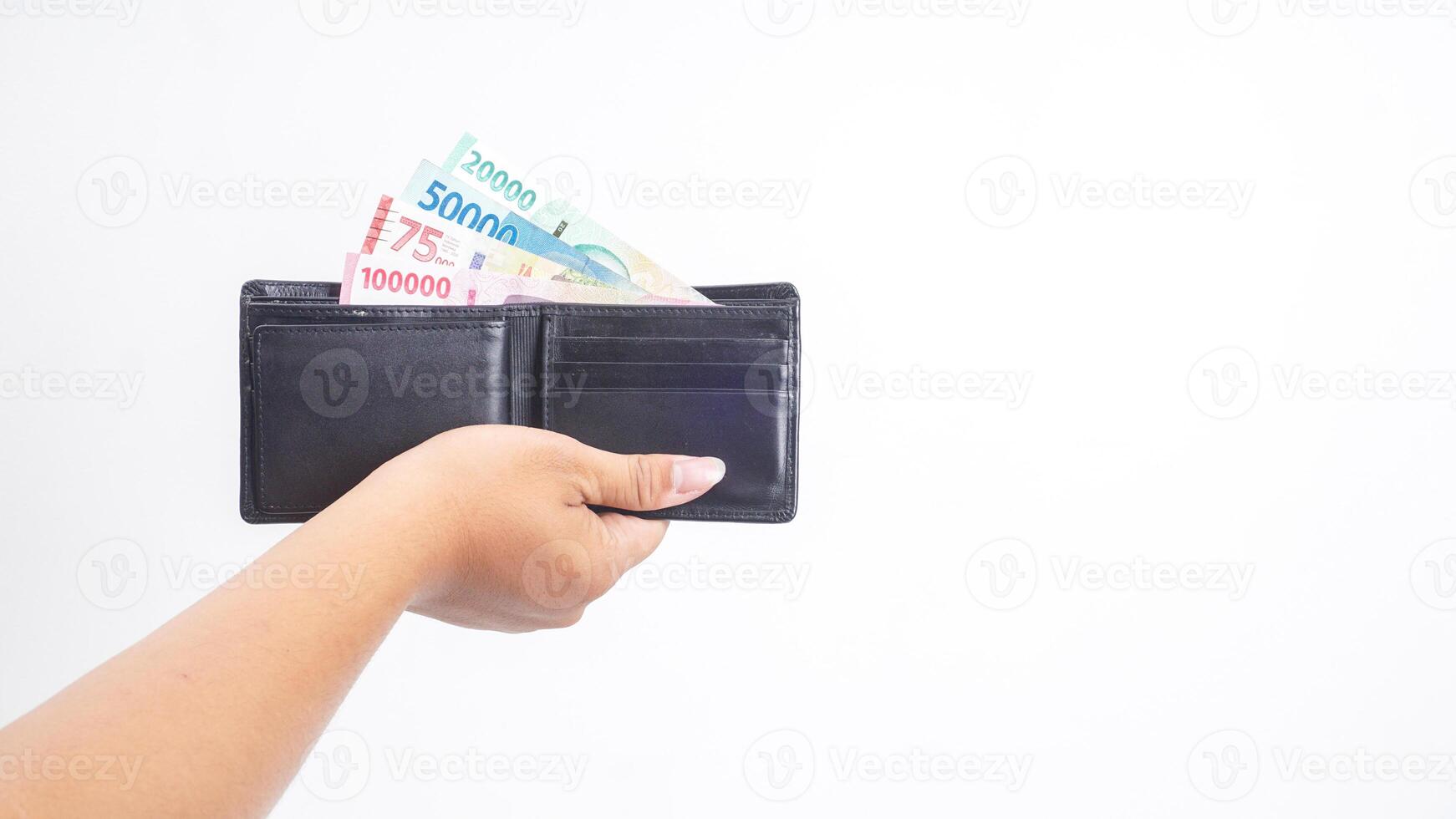 Yogyakarta, Indonesia, 2025 - Hand holding wallet with several Indonesian Rupiah banknotes with different values isolated on white background photo
