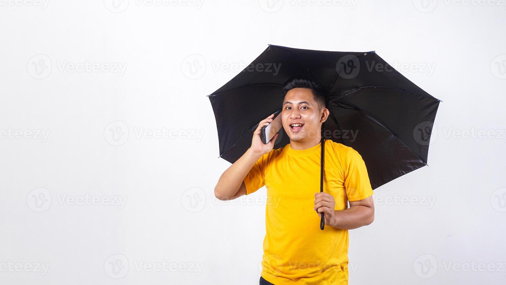 Happy Asian man holds an umbrella while talking on the phone call isolated on white background photo
