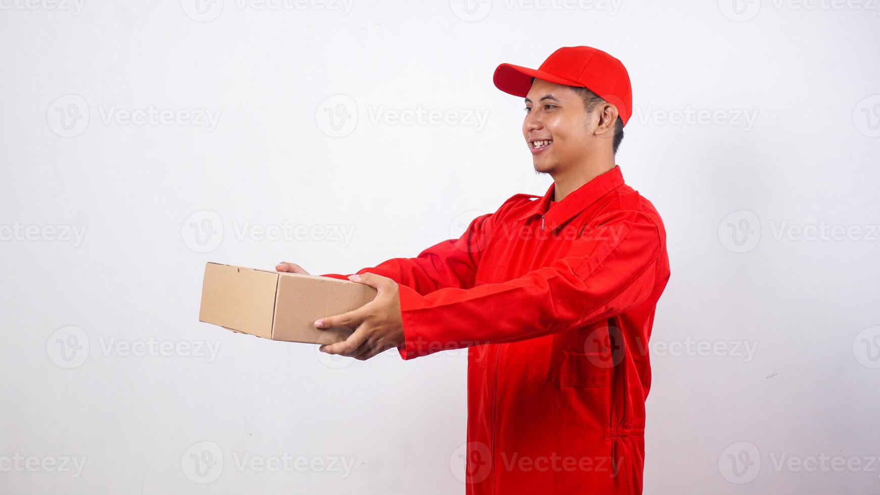 Asian Delivery man in red uniform poses as if he is giving package box parcel to customer isolated on white background photo