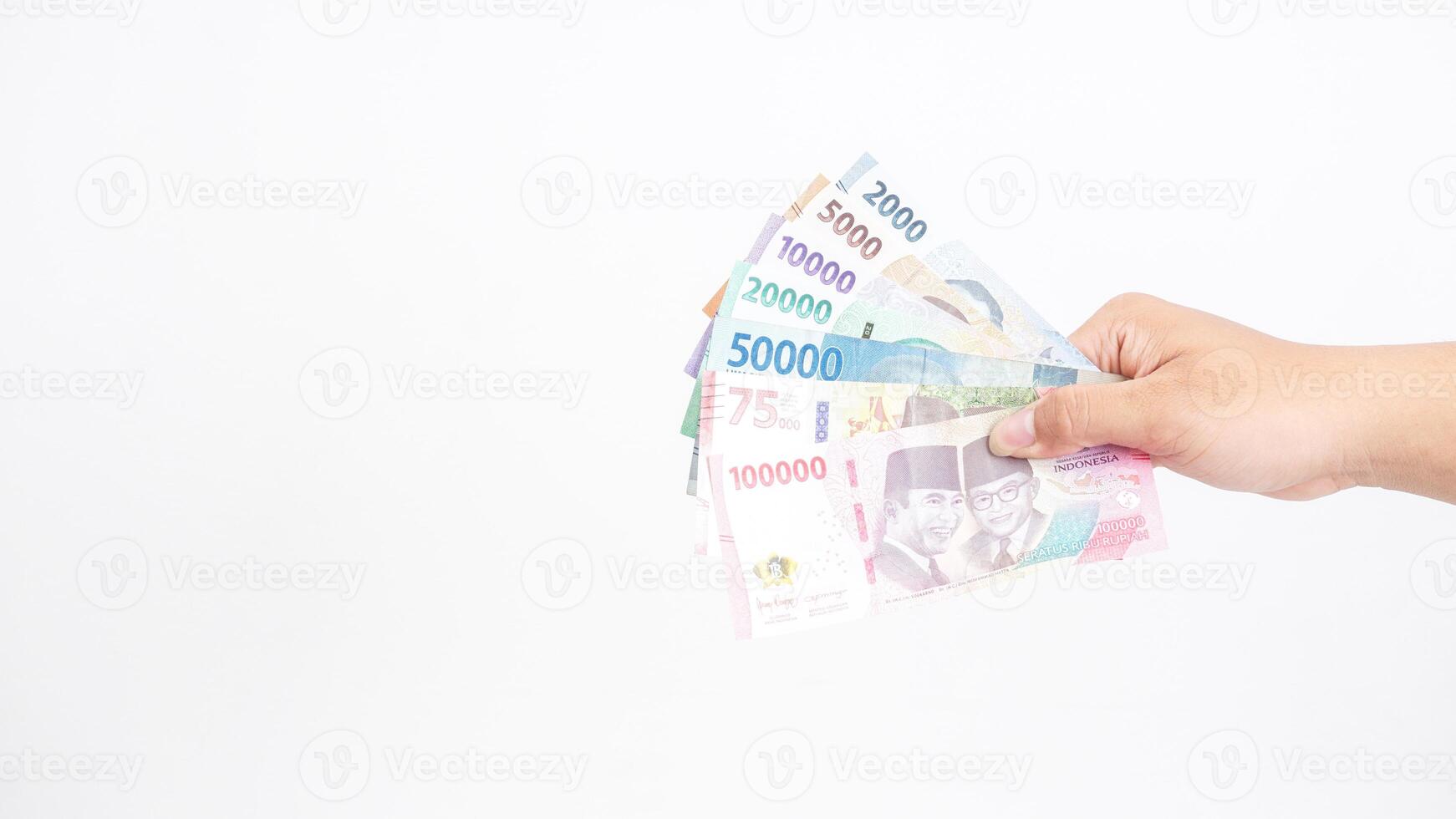 Yogyakarta, Indonesia, 2025 - Hand holds several Indonesian Rupiah banknotes with different values isolated on white background photo