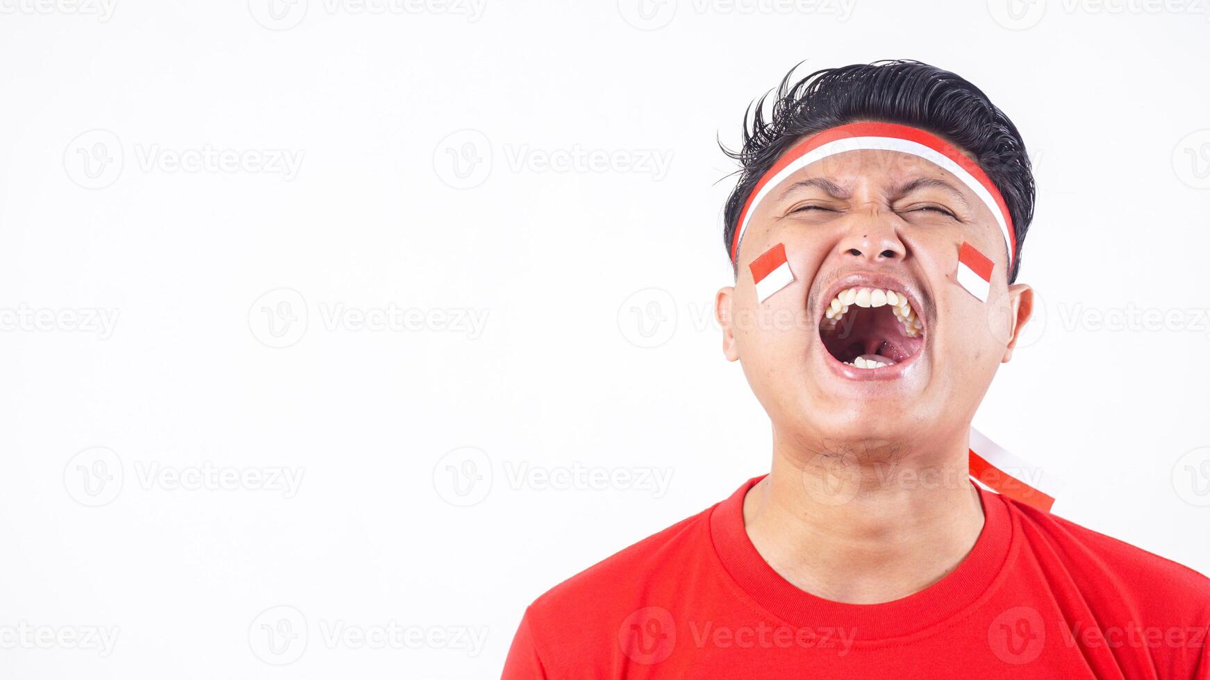 Close up portrait of excited Indonesian man with red and white attributes celebrate independence day of Indonesia on August 17 isolated on white background photo