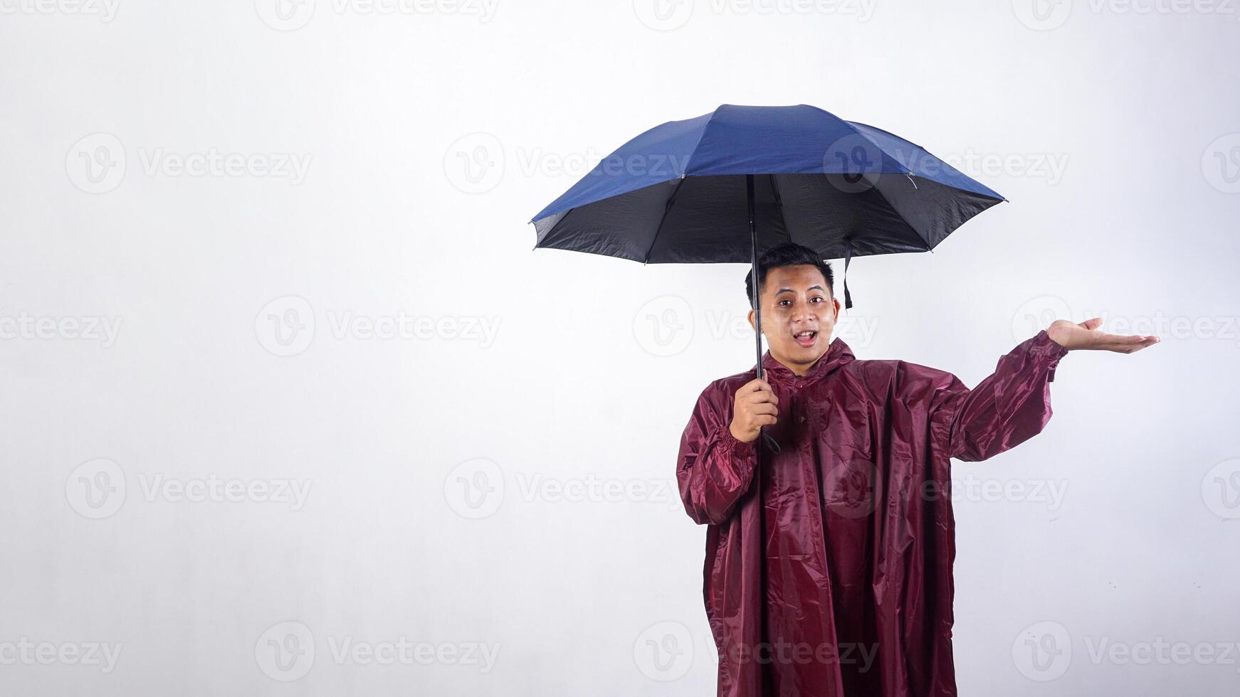 Portrait of Asian man in red raincoat holds umbrella raising his arm to presenting empty space for copy space advertisement isolated on white background photo