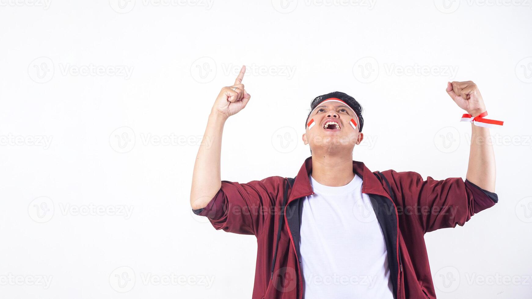 Excited Indonesian man with red and white ribbon wristband to celebrate independence day of Indonesia isolated on white background with copy space photo