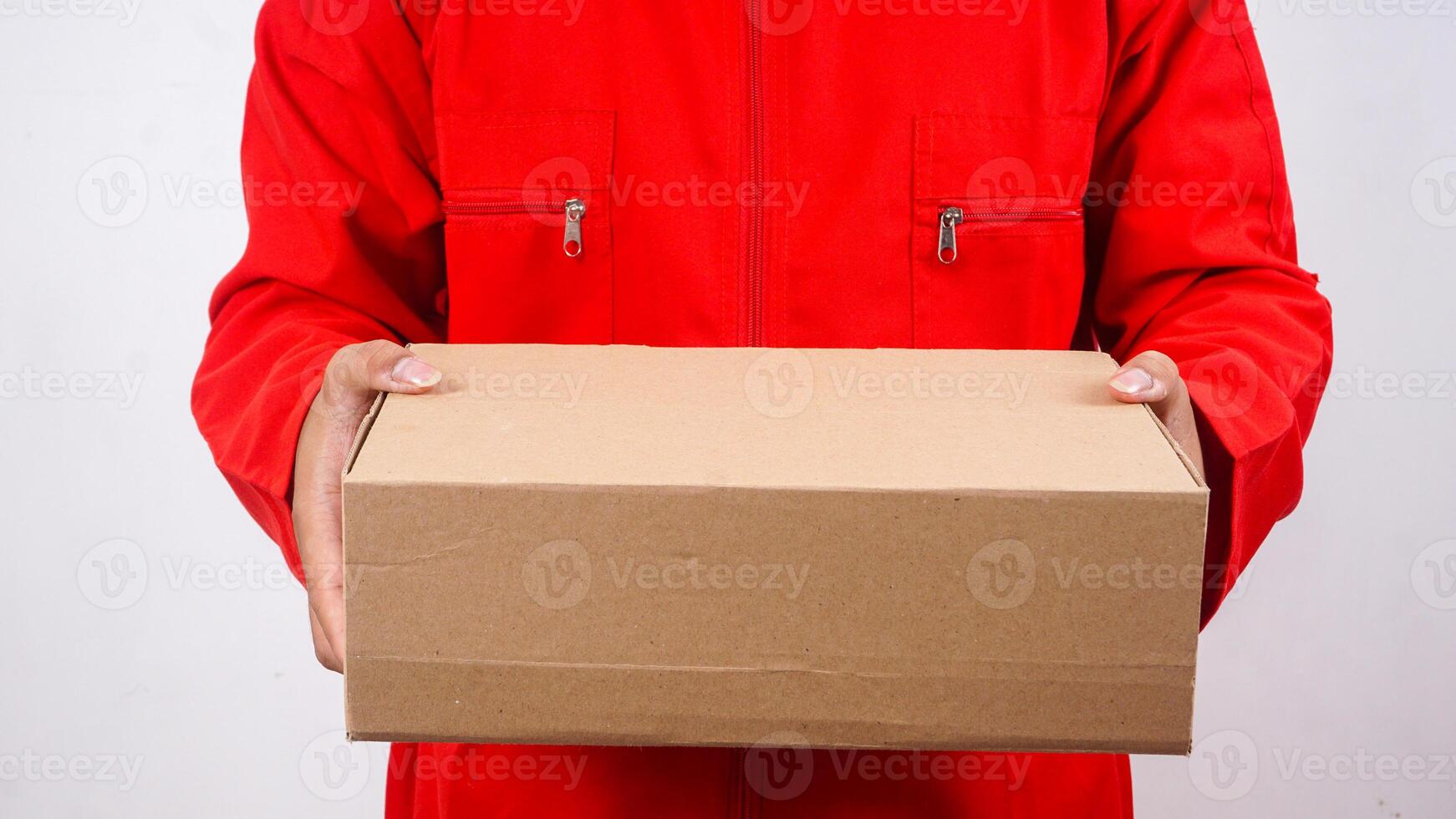 Close up of delivery man in red uniform holding a package box parcel isolated on white background photo