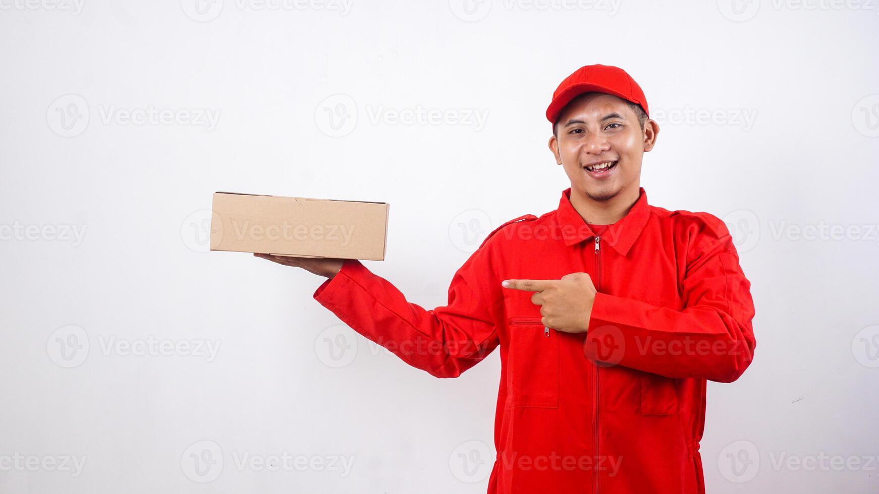 Asian Delivery man in red uniform with package box parcel and pointing at it isolated on white background photo