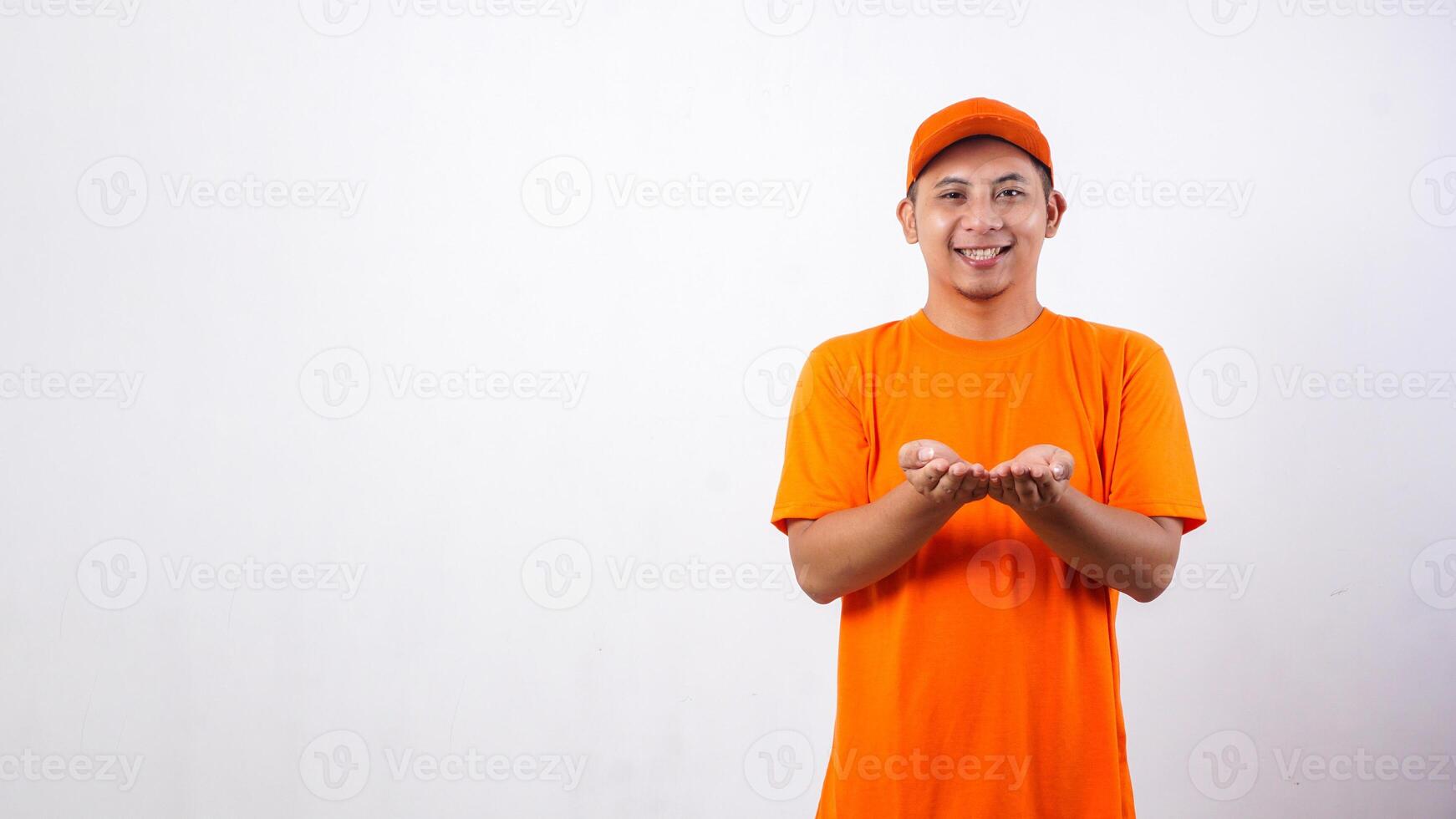 Asian deliveryman in orange t-shirt uniform poses as if he is carrying package box isolated on white background photo