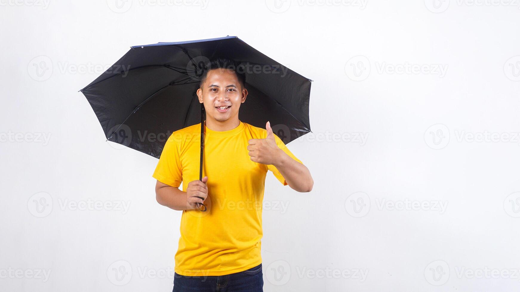 Asian man holds an umbrella and showing his thumb up isolated on white background photo