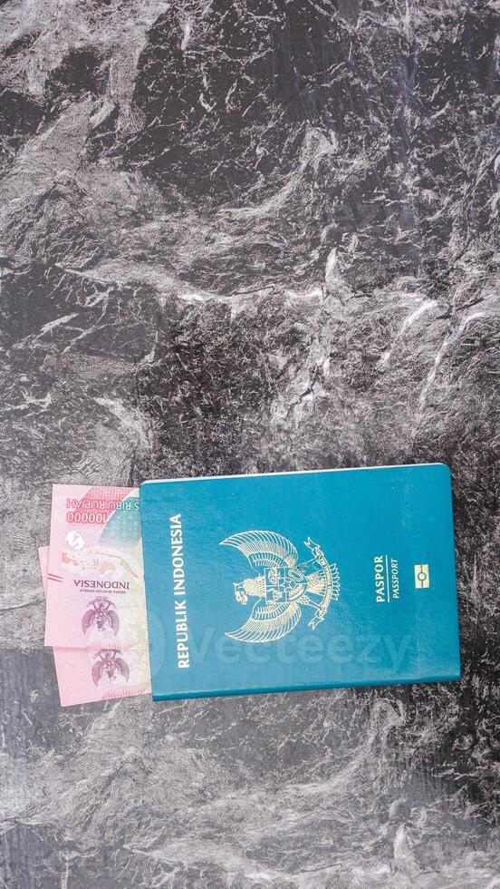 Yogyakarta, Indonesia, 2025 - Indonesian passport with Indonesia Rupiah banknotes inside the passport isolated on marble pattern background photo