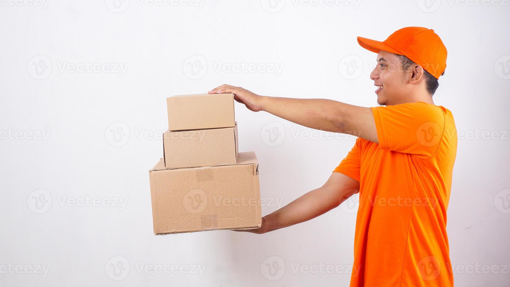 Side view of Portrait of Asian deliveryman in orange t-shirt uniform delivering stack of package boxes parcel to customer isolated on white background photo