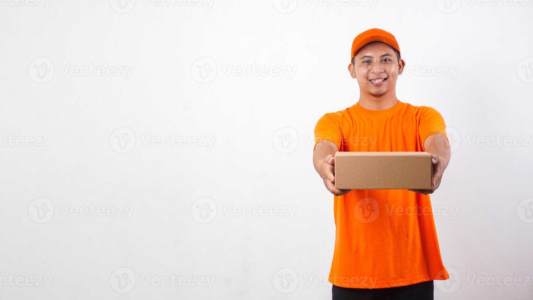 Portrait of Asian deliveryman in orange t-shirt uniform giving a package box parcel to customer isolated on white background photo